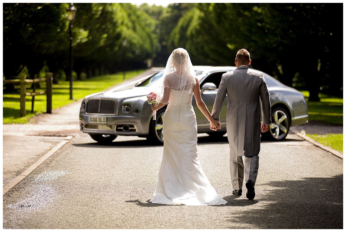 Bride and groom walking down Crewe Hall drive