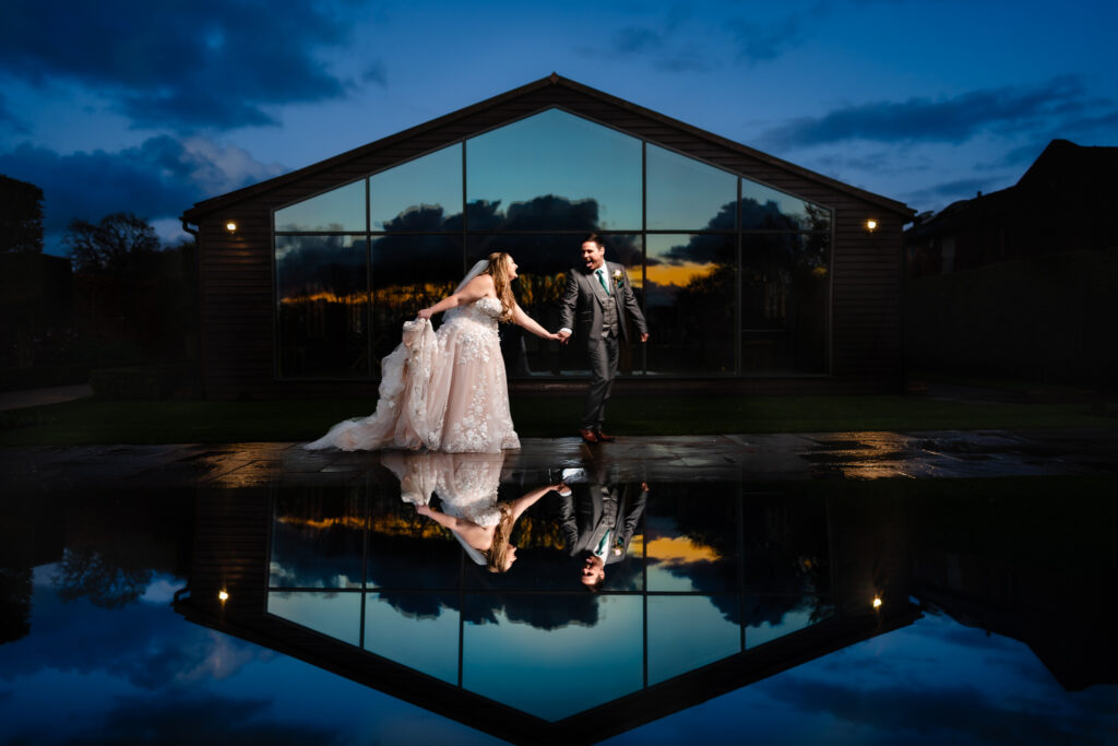 Bride and groom laughing together on a reflective terrace at Merrydale Manor, Cheshire wedding photographer