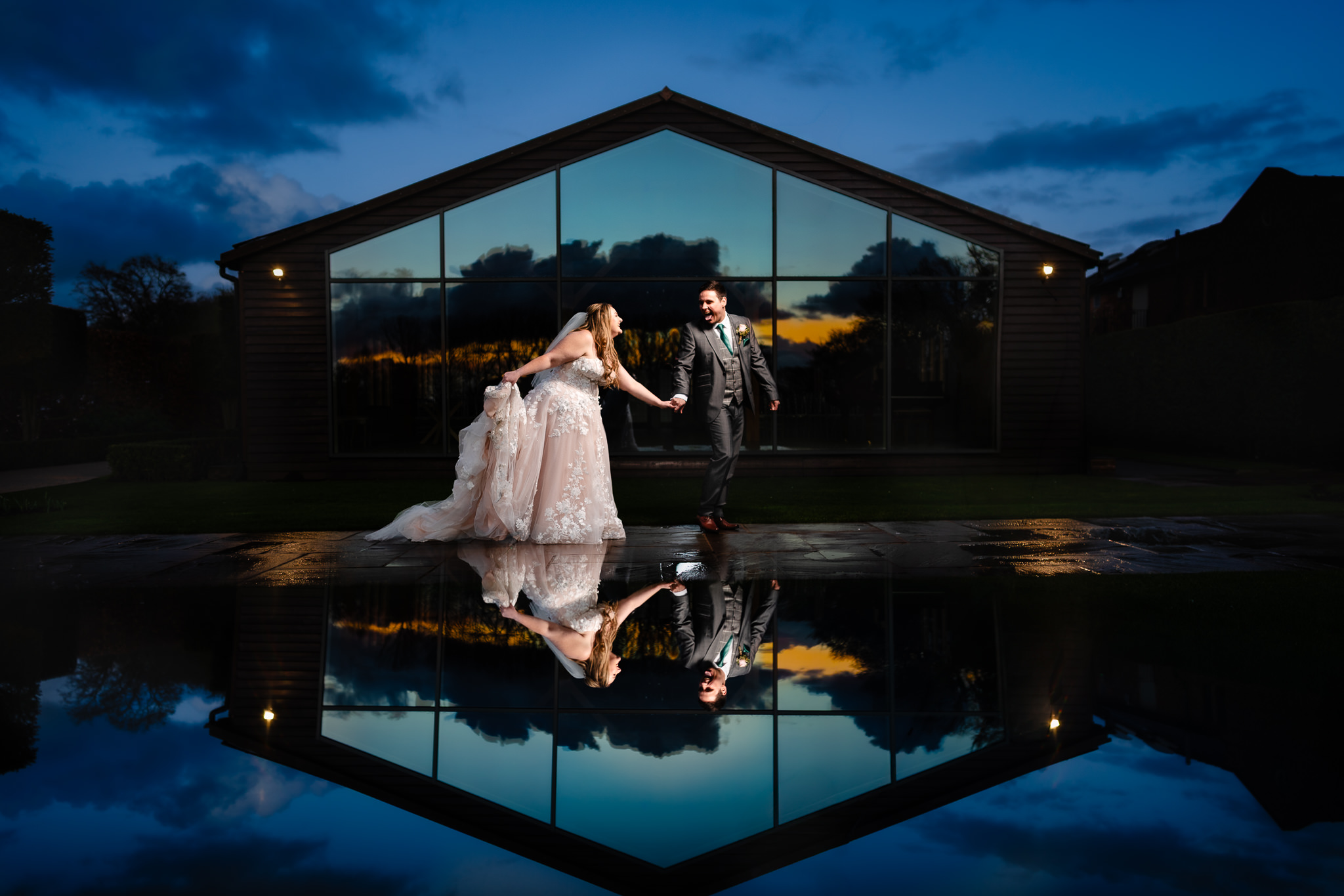Bride and groom laughing together on a reflective terrace at Merrydale Manor, Cheshire wedding photographer