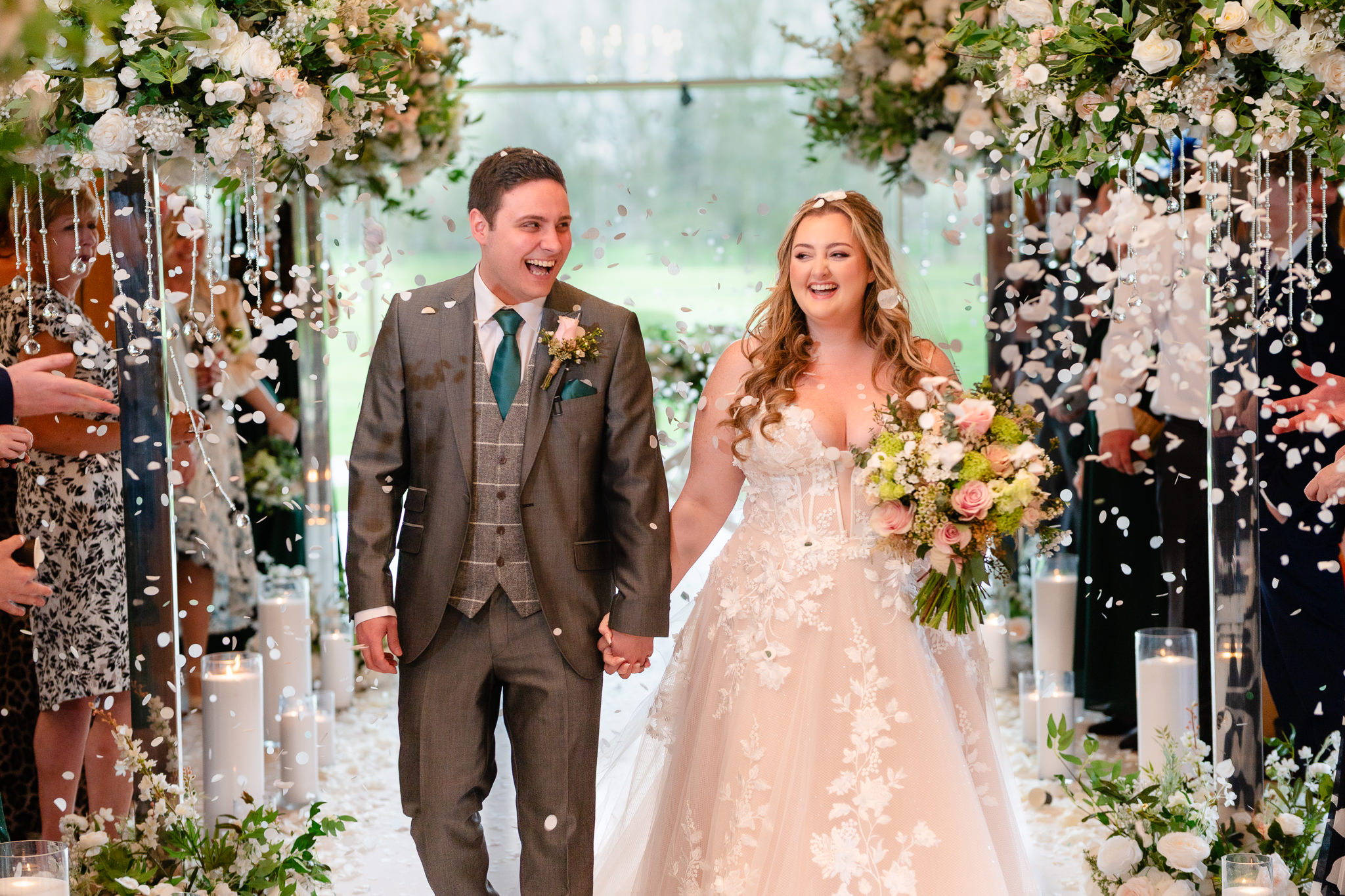 Bride and groom laughing as they walk up the aisle through confetti at Merrydale Manor