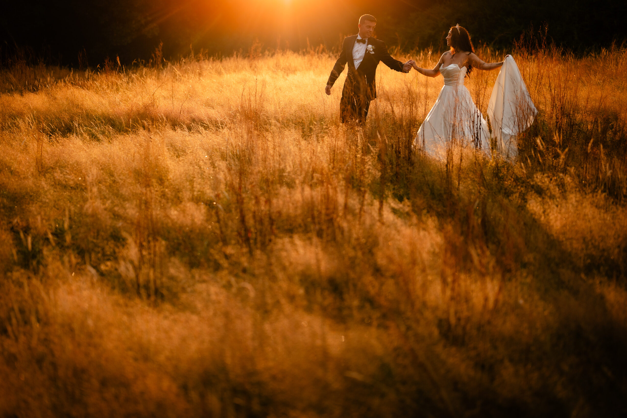 Bride and groom dancing together in a sunlit field at golden hour at Rainhill Hall, Liverpool wedding photographer