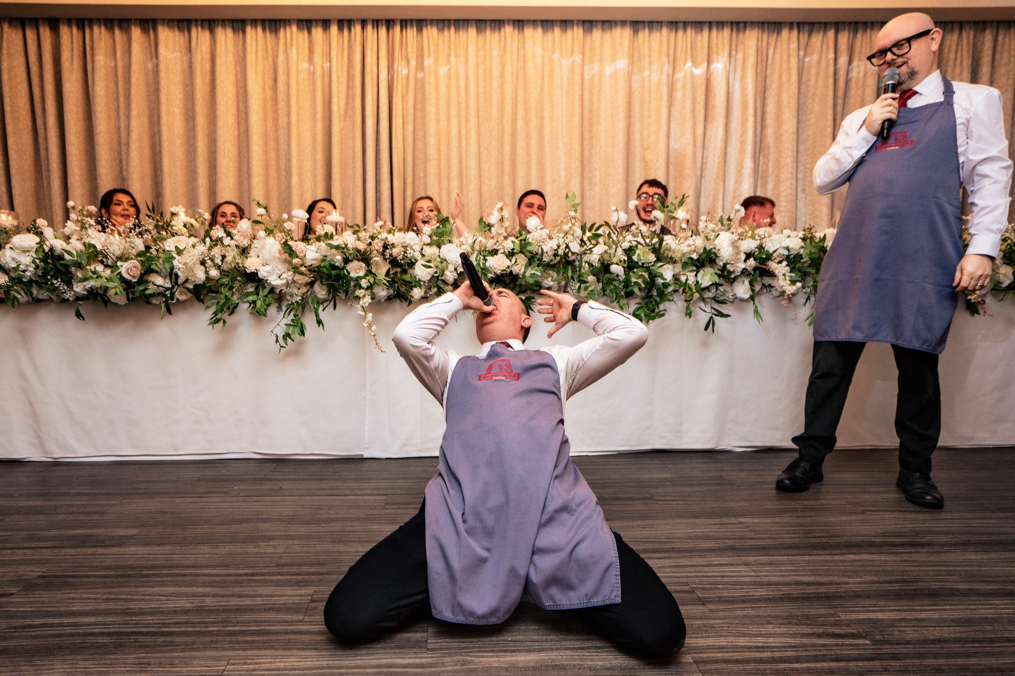 Singing Waiter kneeling and belting out a song beside the top table at Merrydale Manor wedding breakfast