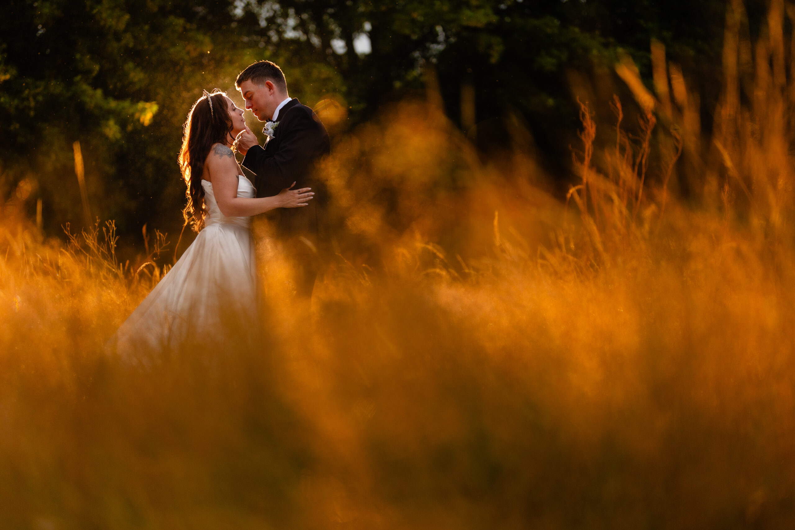 Bride and groom sharing a golden hour kiss in a field, Rainhill Hall wedding photographer