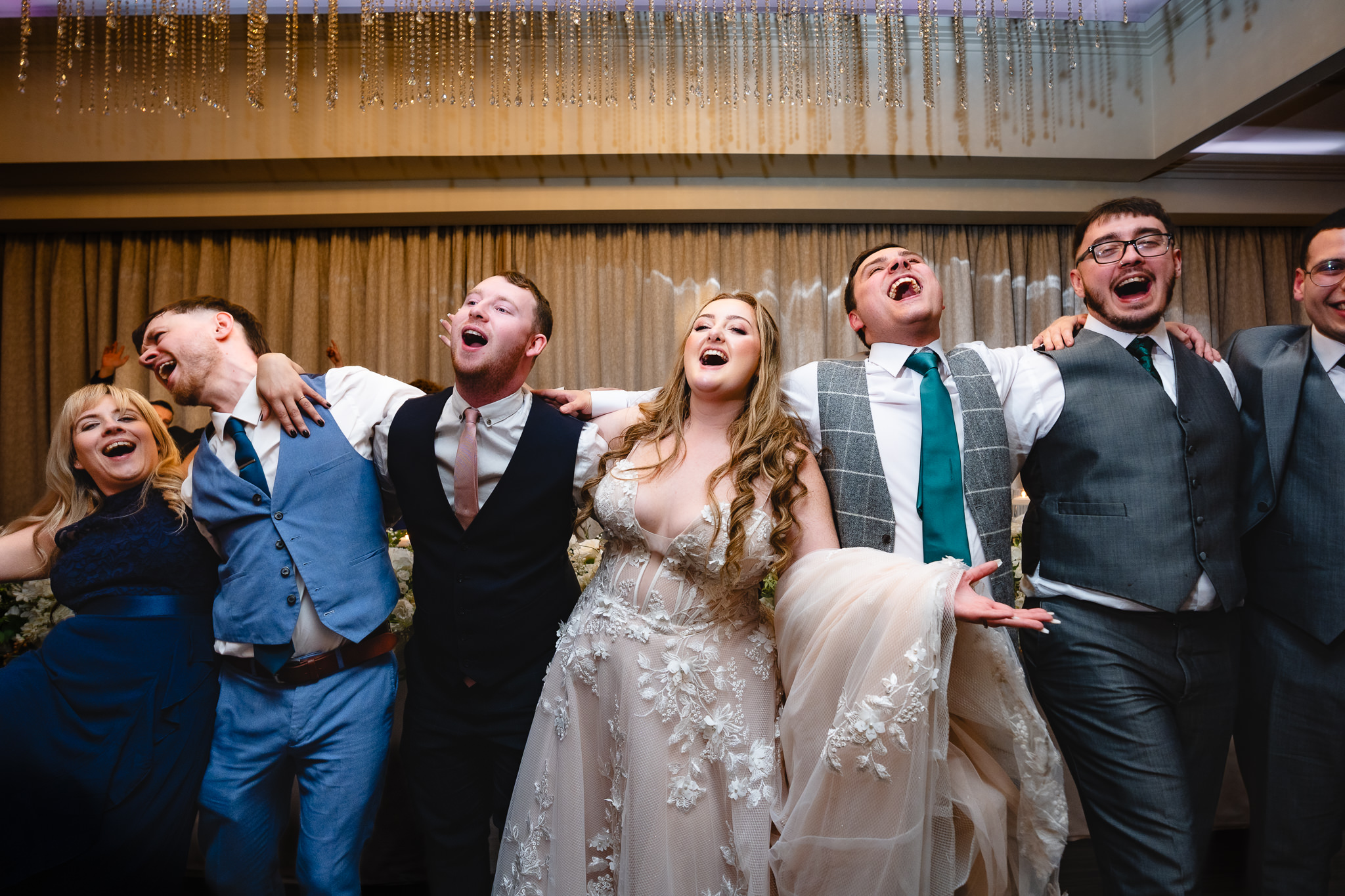 Bride, groom and wedding party singing along arm in arm with the Singing Waiters at Merrydale Manor