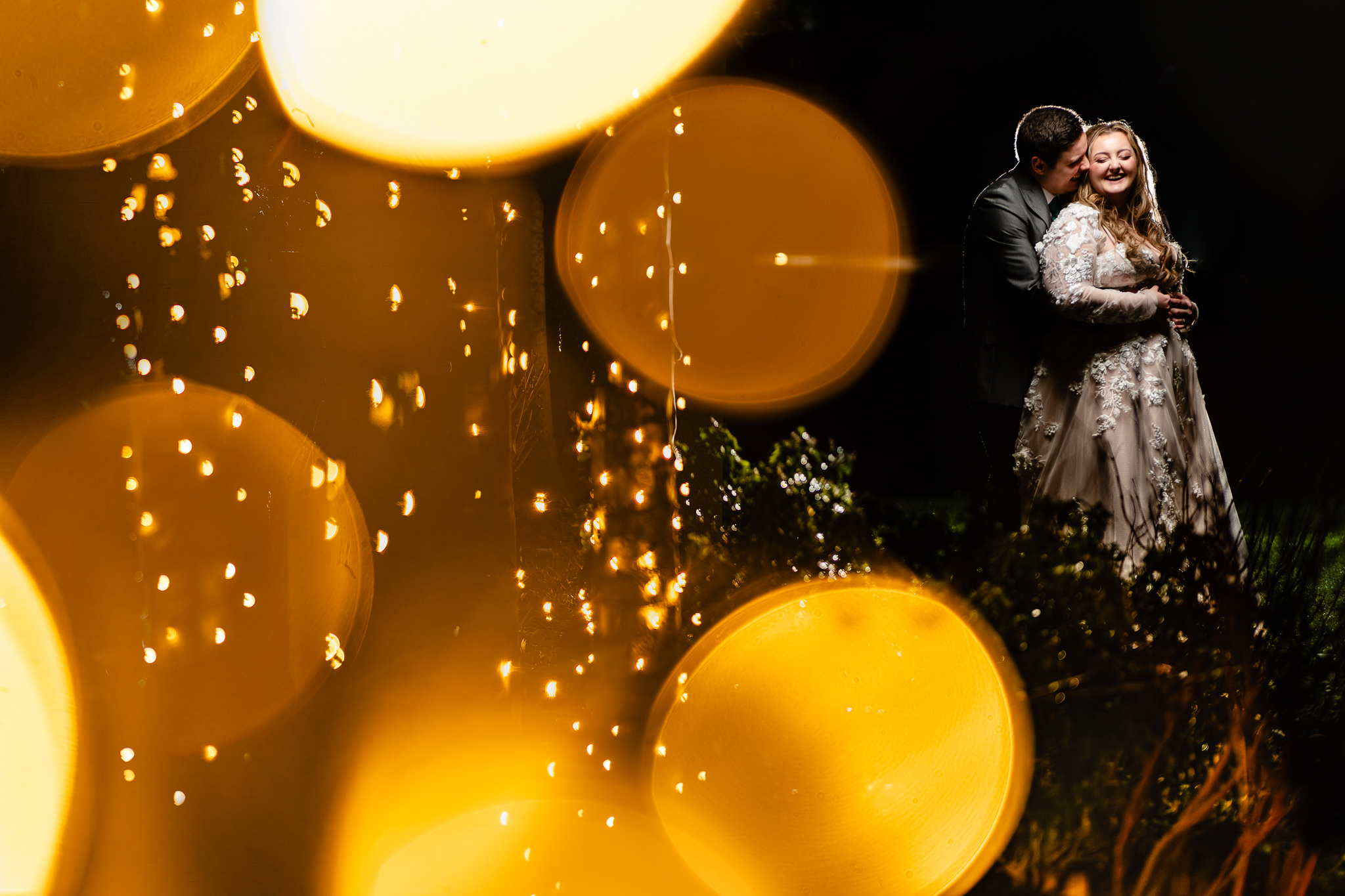 Bride and groom embracing through fairy light bokeh in the evening at Merrydale Manor, Cheshire wedding photographer