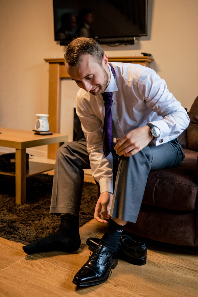 Groom lacing his black shoes in the living room before his Merrydale Manor wedding, Cheshire wedding photographer