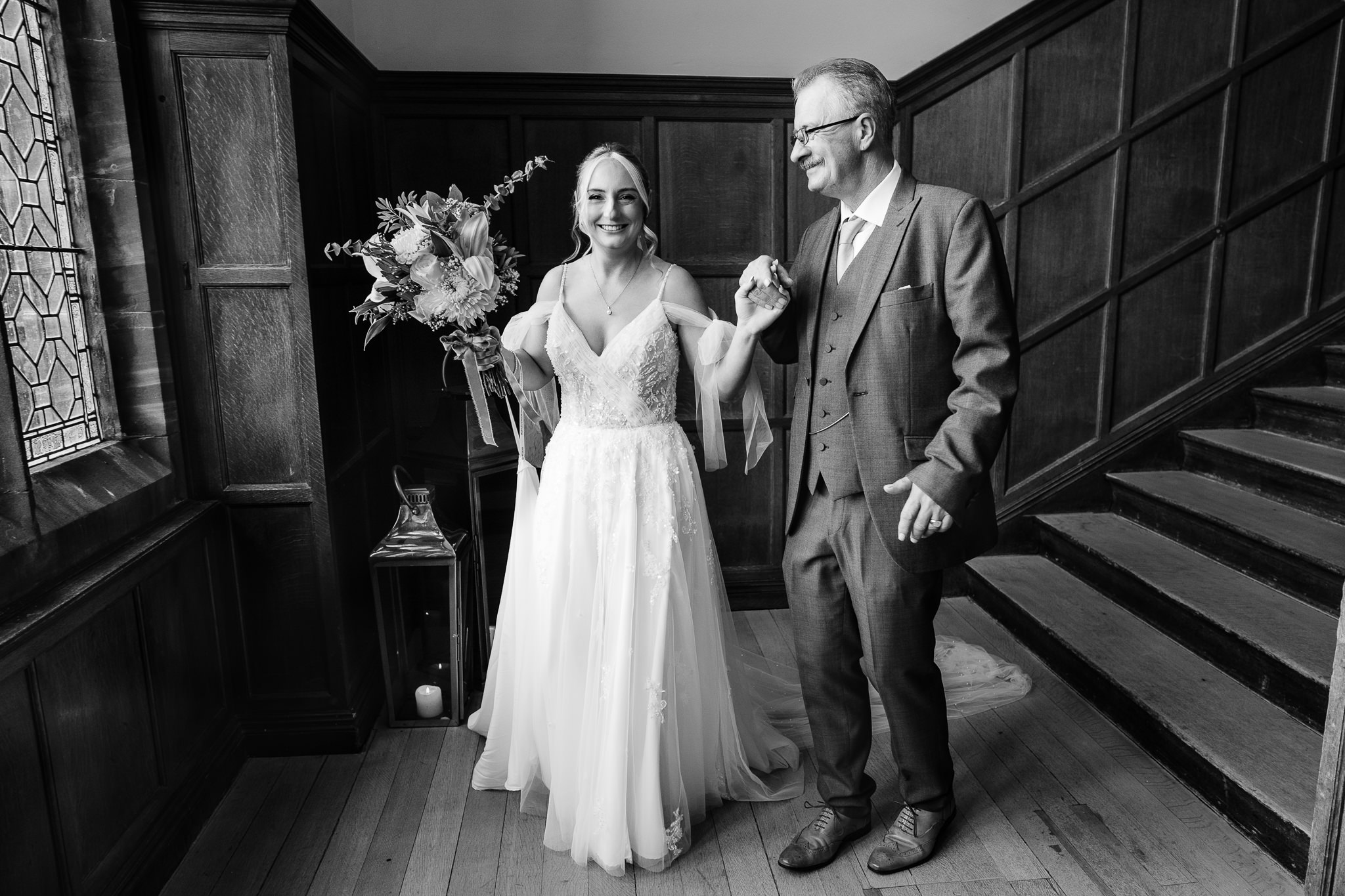 Black and white photo of the bride holding hands with her dad on the staircase at Salt House before heading down to the ceremony