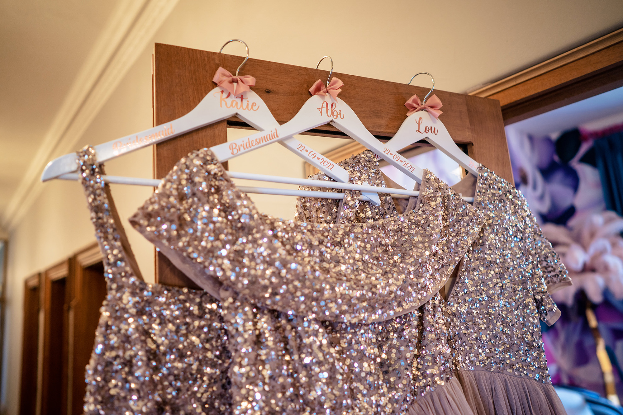 Bridesmaids sequin dresses on personalised hangers reading Katie, Abi and Lou before a Standon Hall wedding