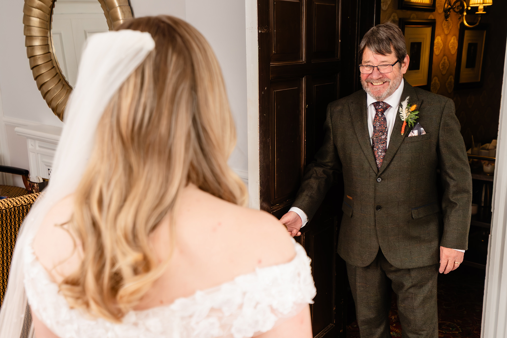 The bride catches sight of her dad waiting in the doorway in his tweed suit and buttonhole, Crewe Hall wedding photographer
