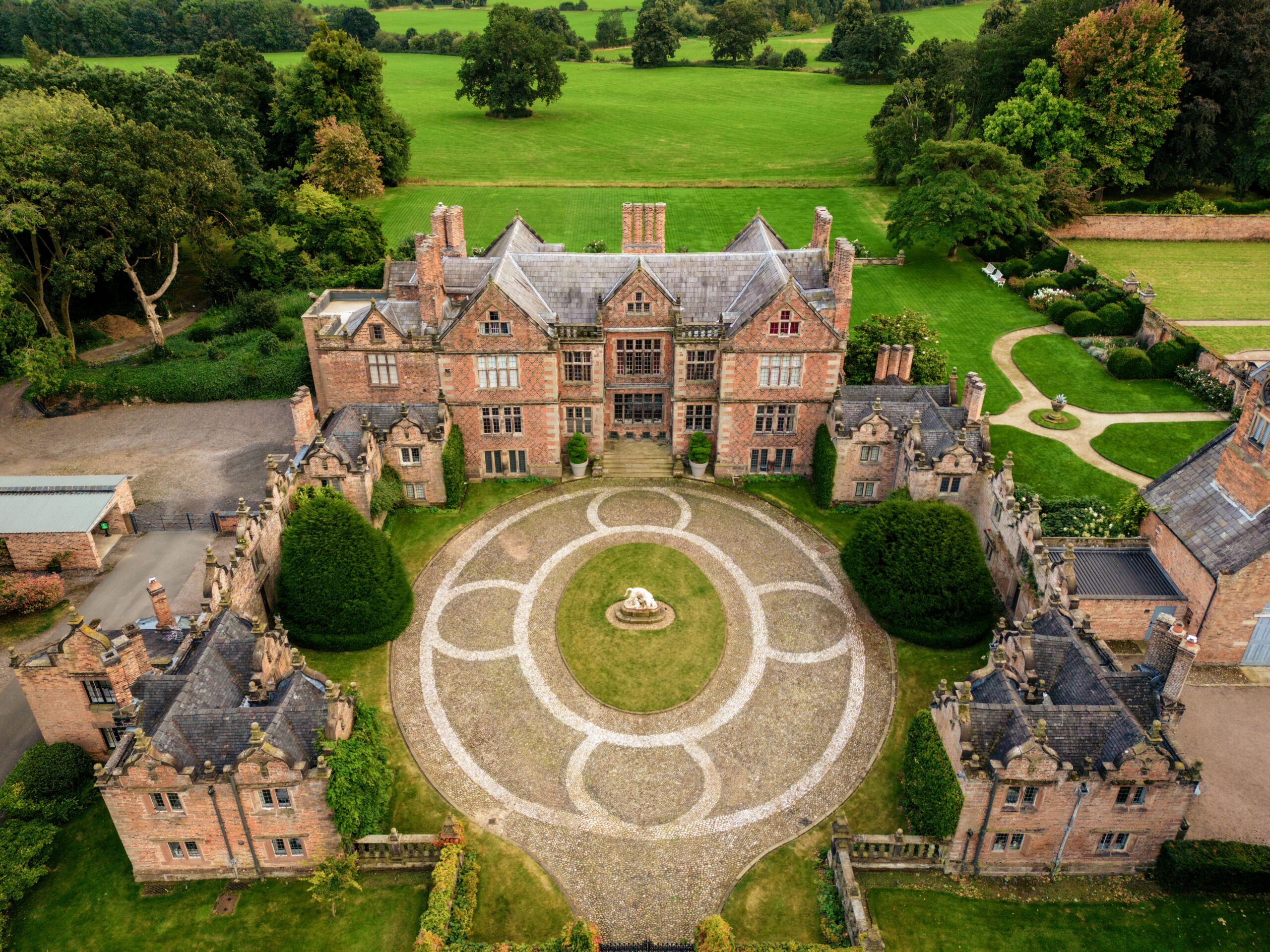 Aerial view of Dorfold Hall and its formal gardens surrounded by Cheshire parkland