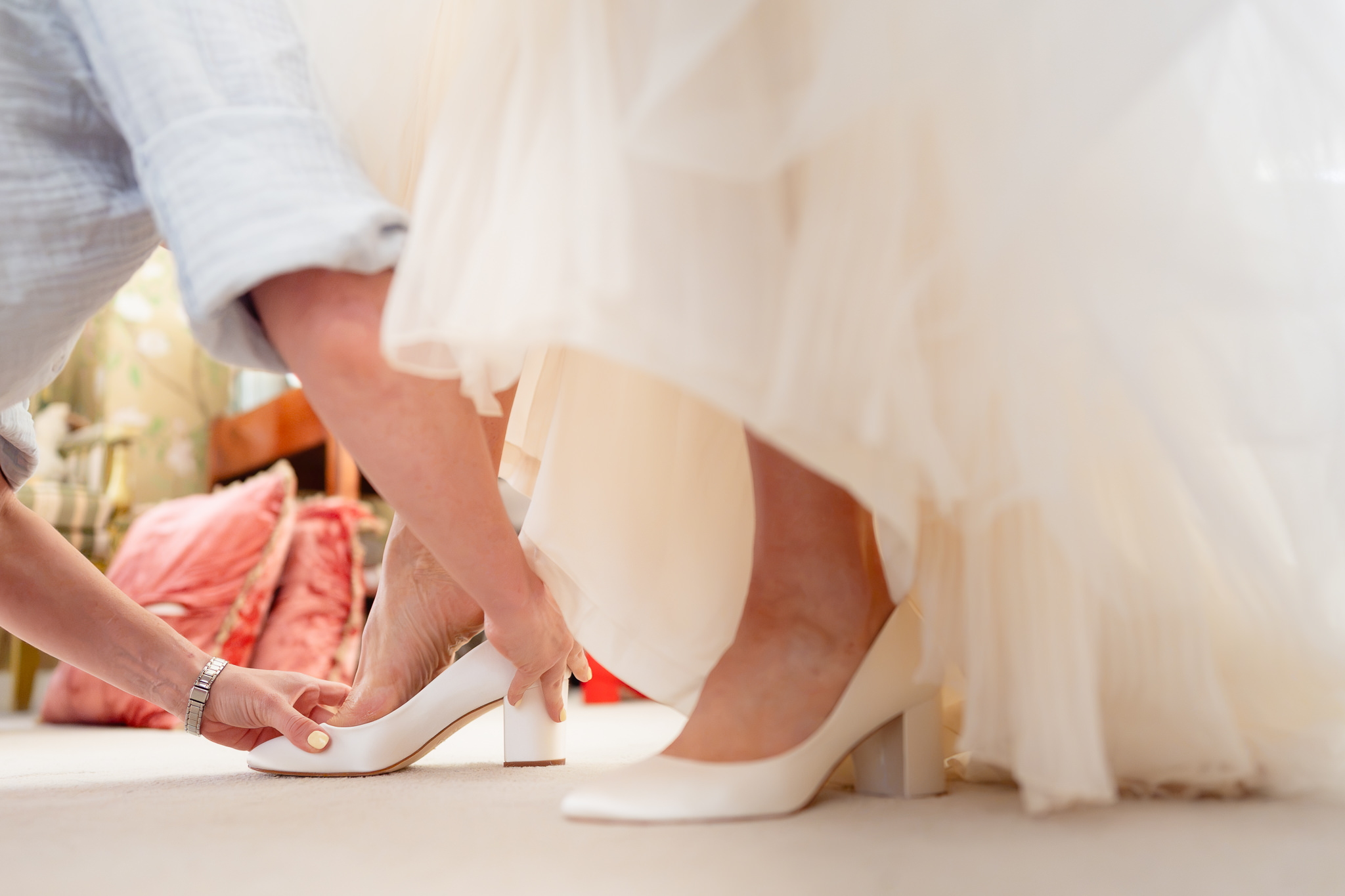 Bride stepping into her white block heel wedding shoes