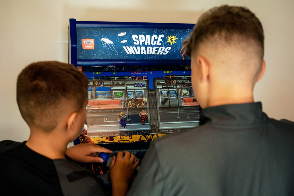 Two boys playing a Space Invaders arcade machine while the boys get ready, Merrydale Manor wedding photographer