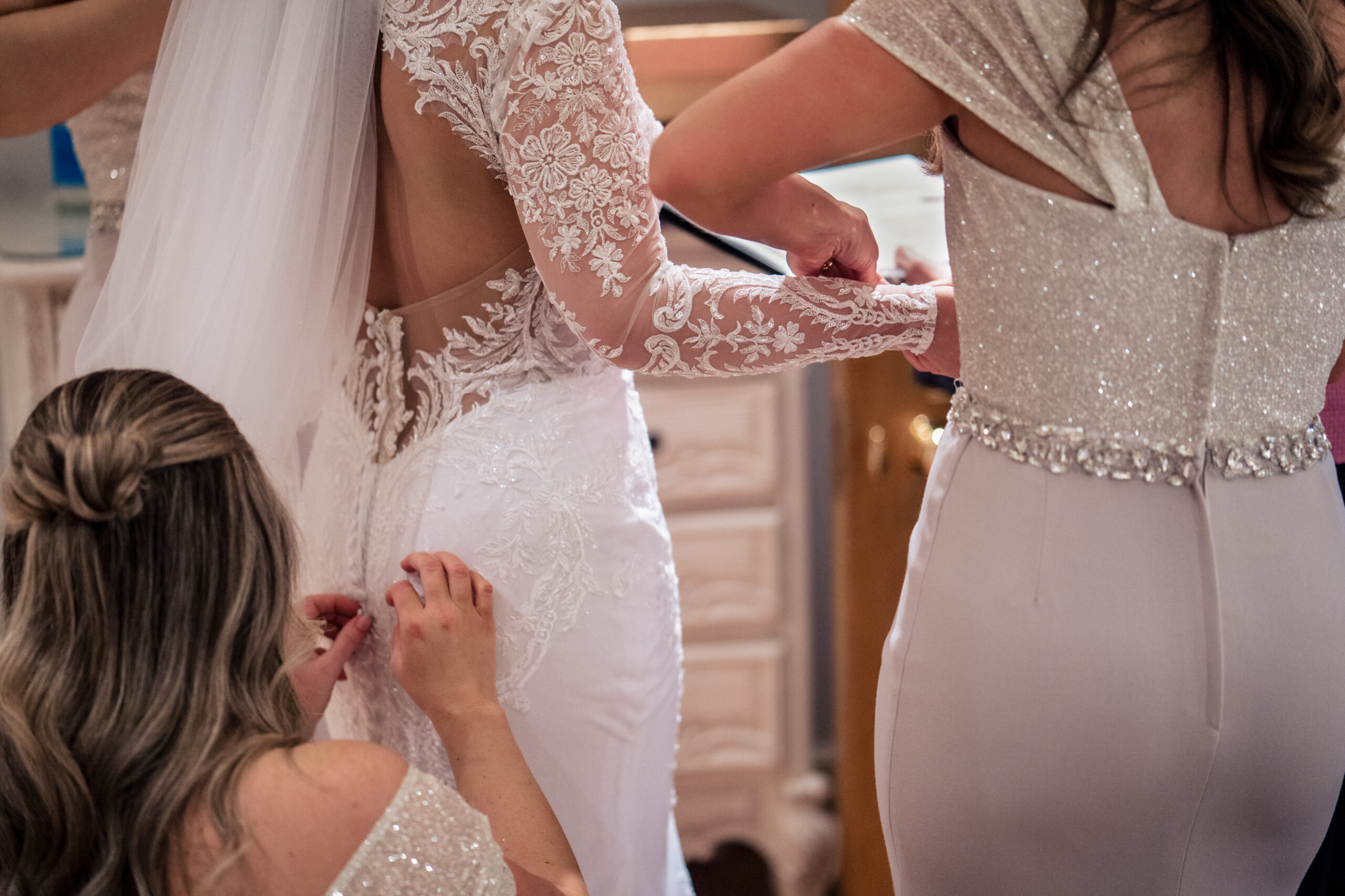 Careful hands fastening the buttons down the back of Abbie’s lace wedding dress, Cheshire wedding photographer
