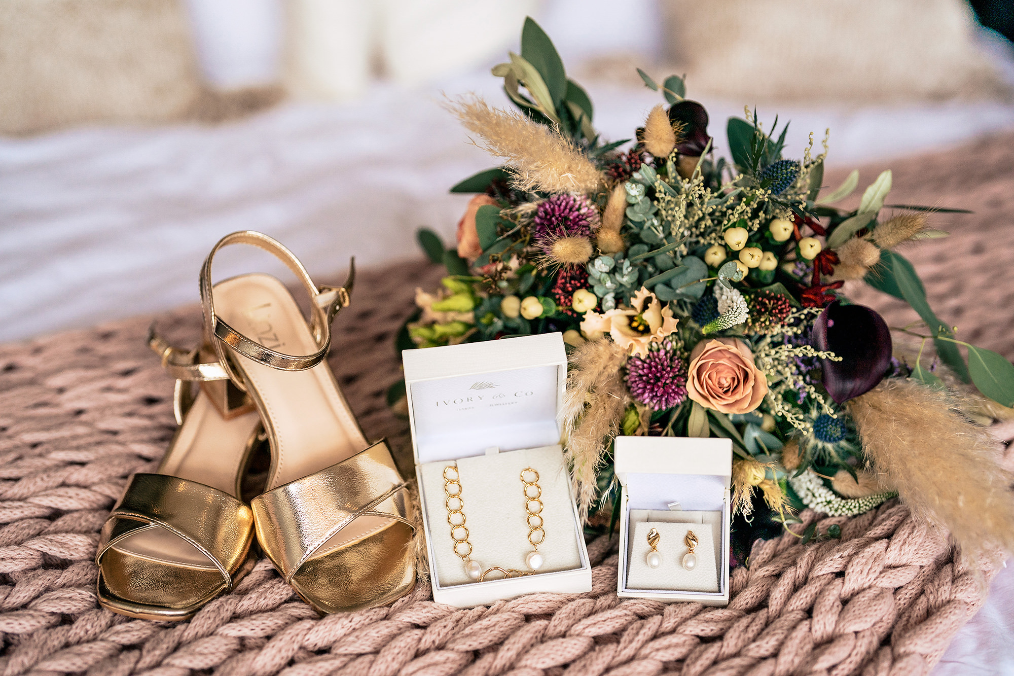 Bridal flatlay of shoes, jewellery and Chloe’s Buttercup & Daisies bouquet