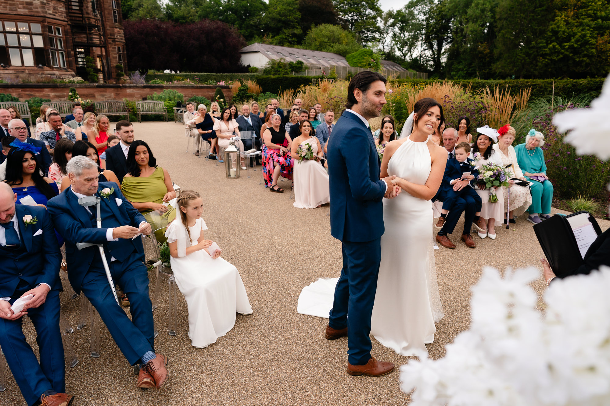 Bride and groom holding hands in front of their guests during the wedding ceremony at Salt House, Staffordshire
