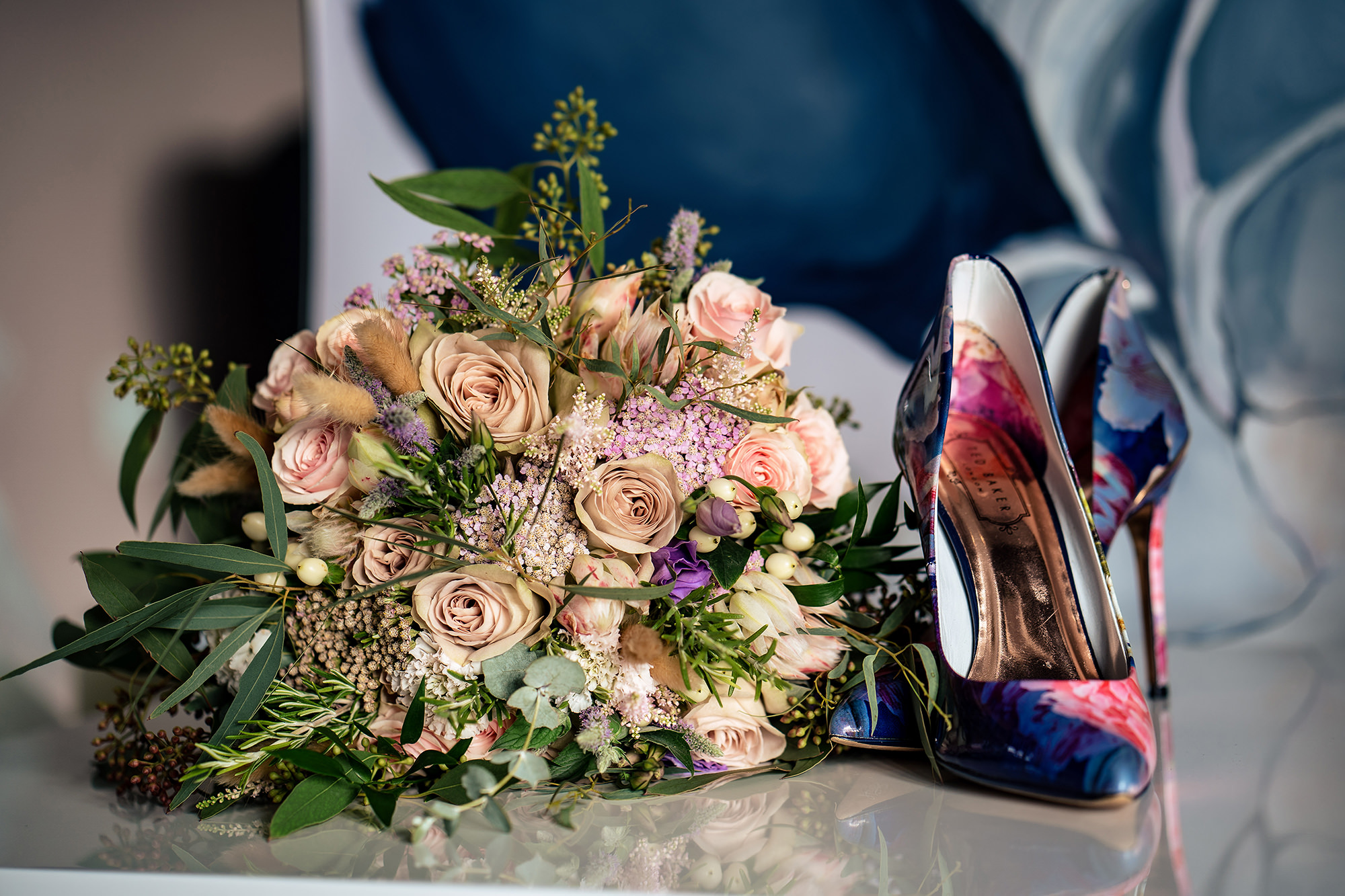 Pink rose bouquet next to bold floral wedding shoes, Standon Hall wedding photographer