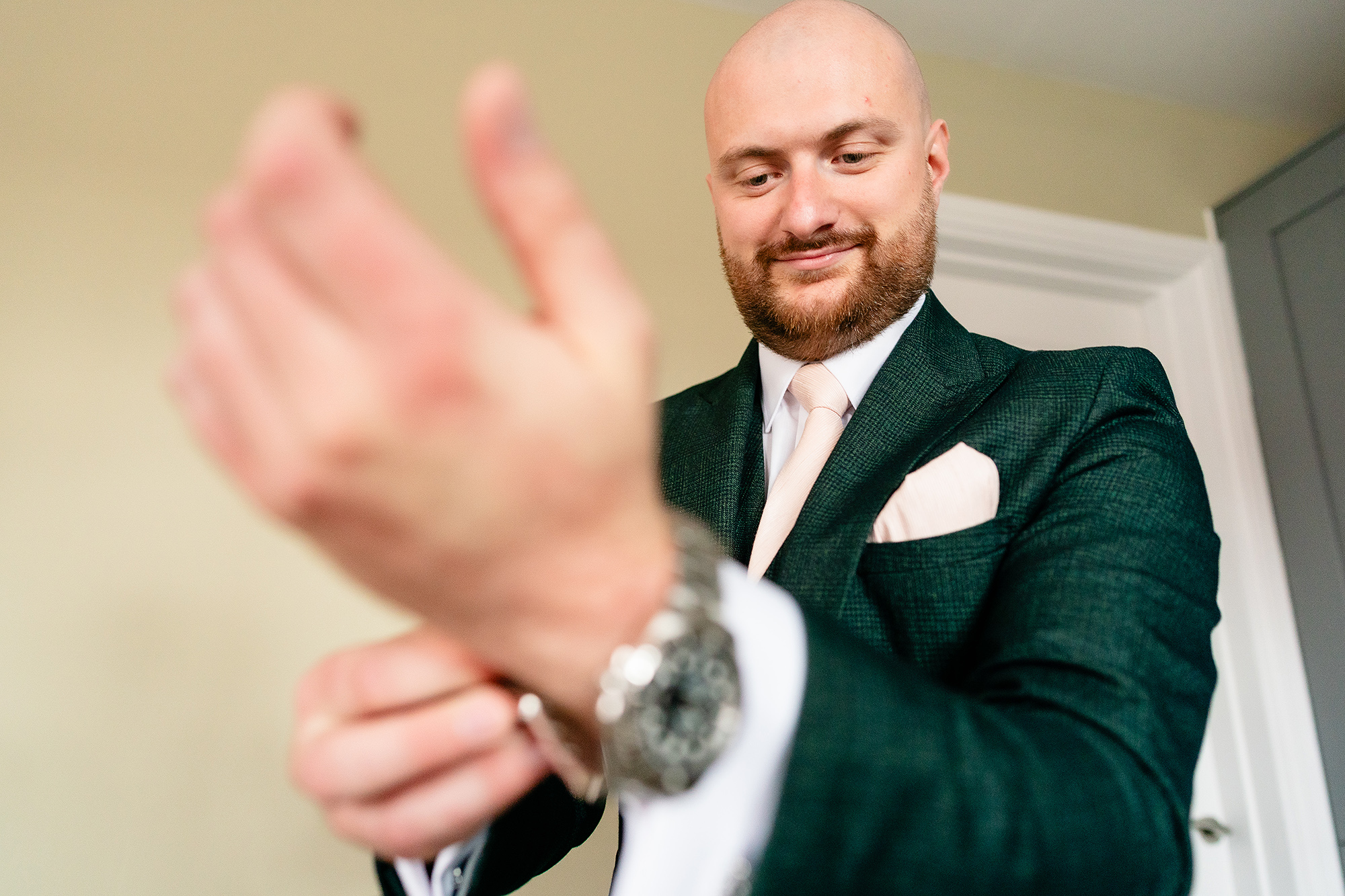 Pete buttoning his shirt cuffs while getting ready in Nantwich before his Wrenbury Hall wedding