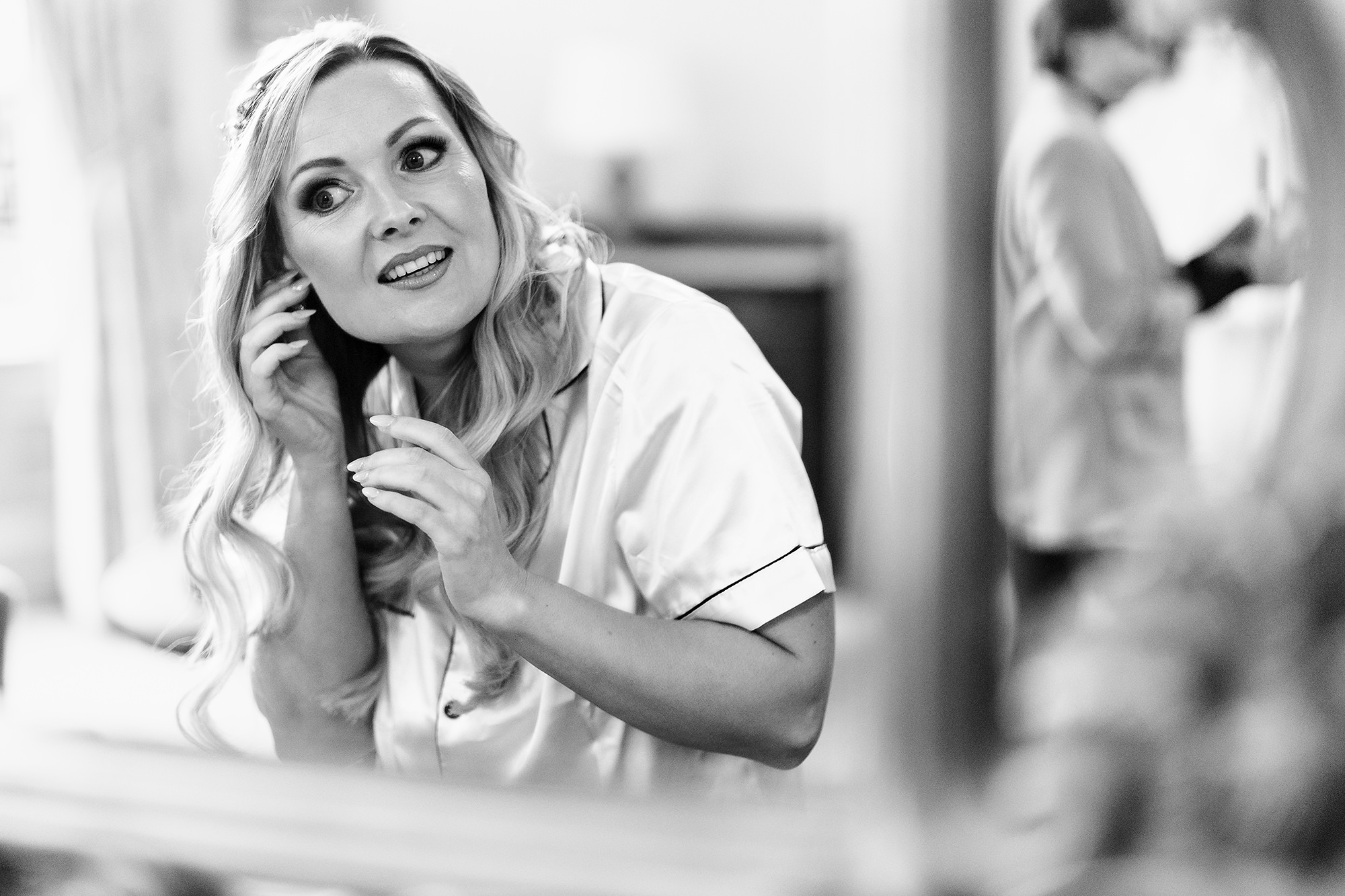 Black and white photograph of the bride on the phone in her dressing gown, hand to her face