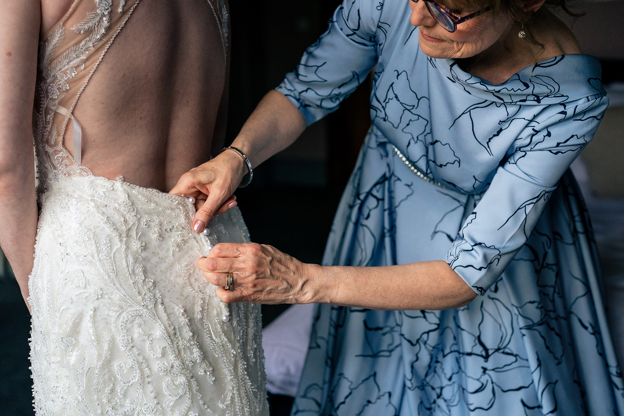 Close up of the bride’s mum fastening her dress on the morning of the wedding, Salt House wedding photographer