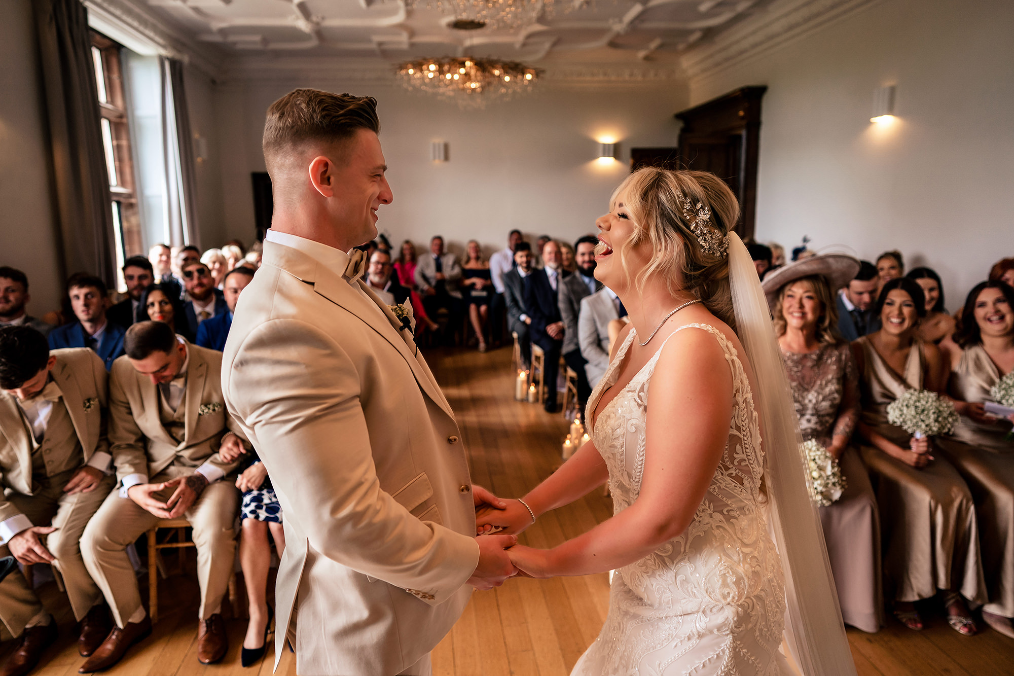 Jess and Cy laughing together while holding hands during their wedding ceremony at Salt House, Staffordshire