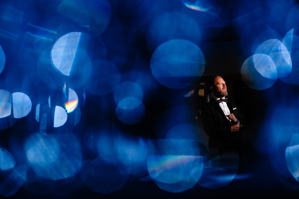 Glynn in black tie framed by blue out of focus light, groom portrait at Swancar Farm Country House, Nottingham wedding photographer