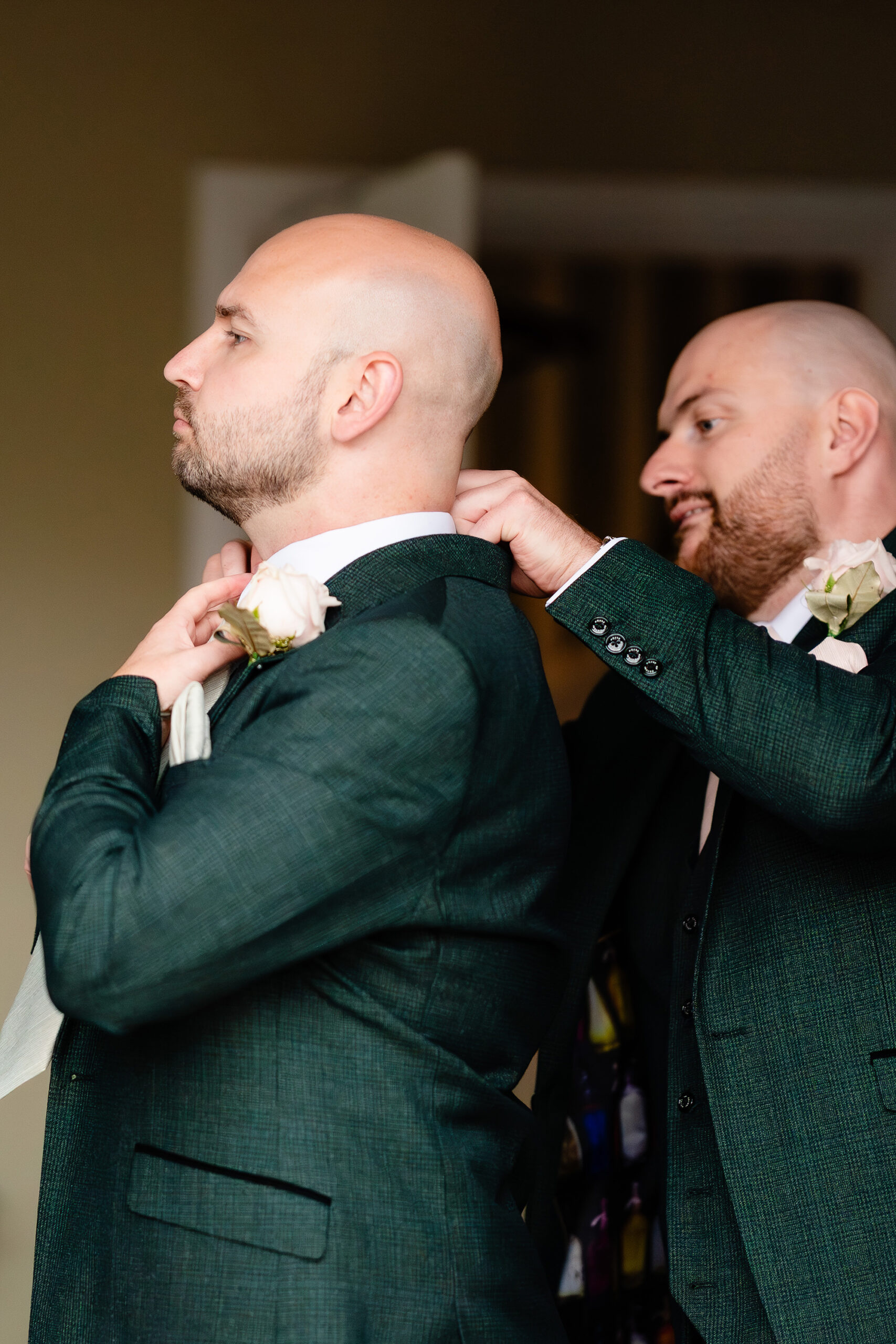 Two groomsmen straightening each other’s ties before heading to St Mary’s Church