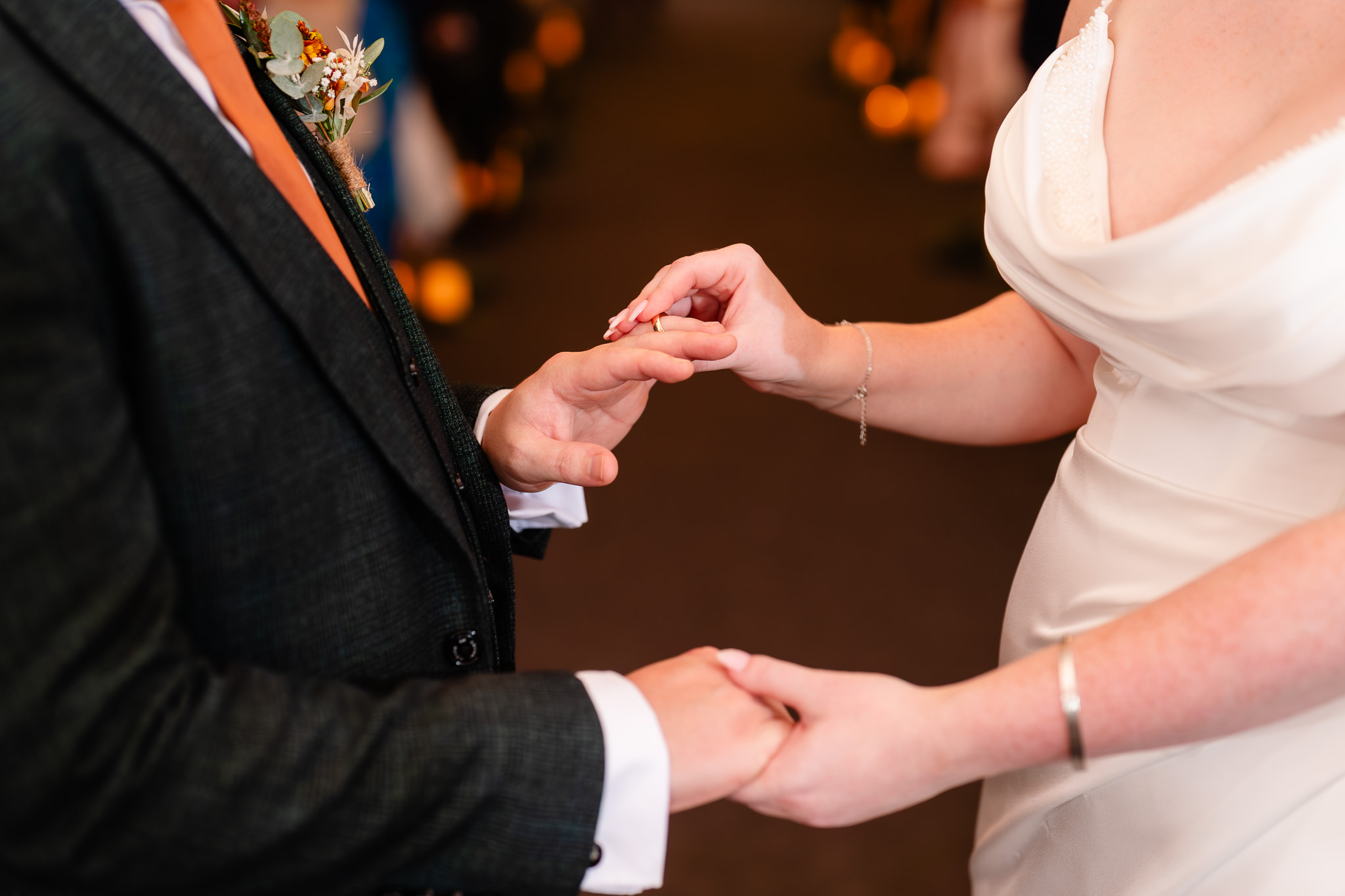 Close up of the bride sliding the wedding ring onto the groom's finger during the ring exchange, Heaton House Farm wedding