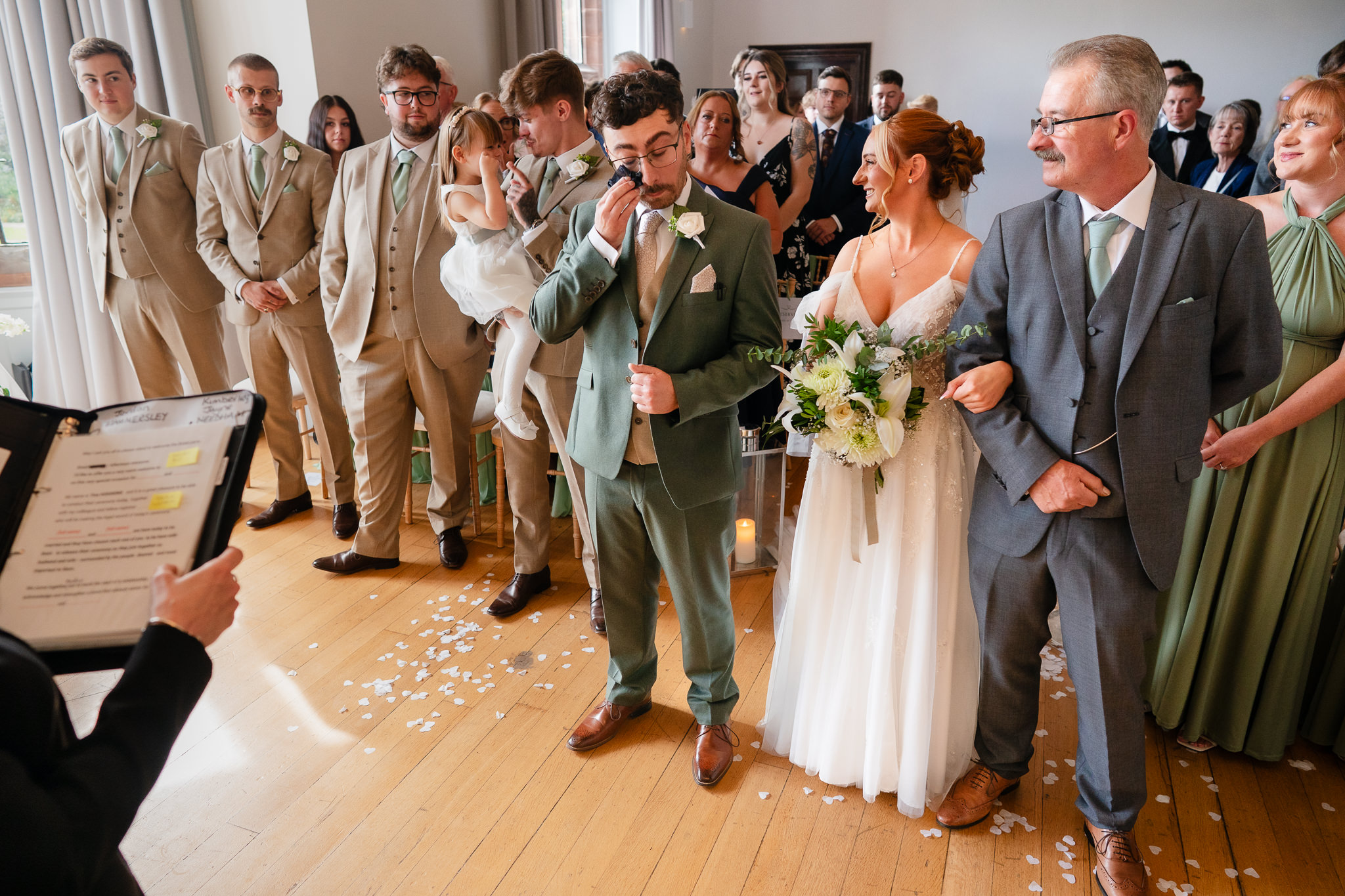 Close up of the bride sharing a laugh with her groom and her dad at the top of the aisle