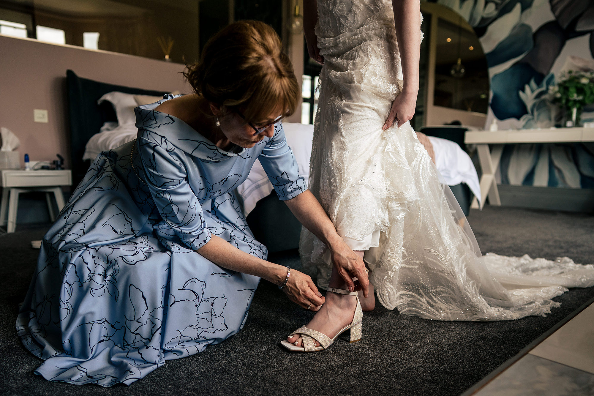 Bride’s mum kneeling to help her into her wedding shoes, Salt House wedding photographer