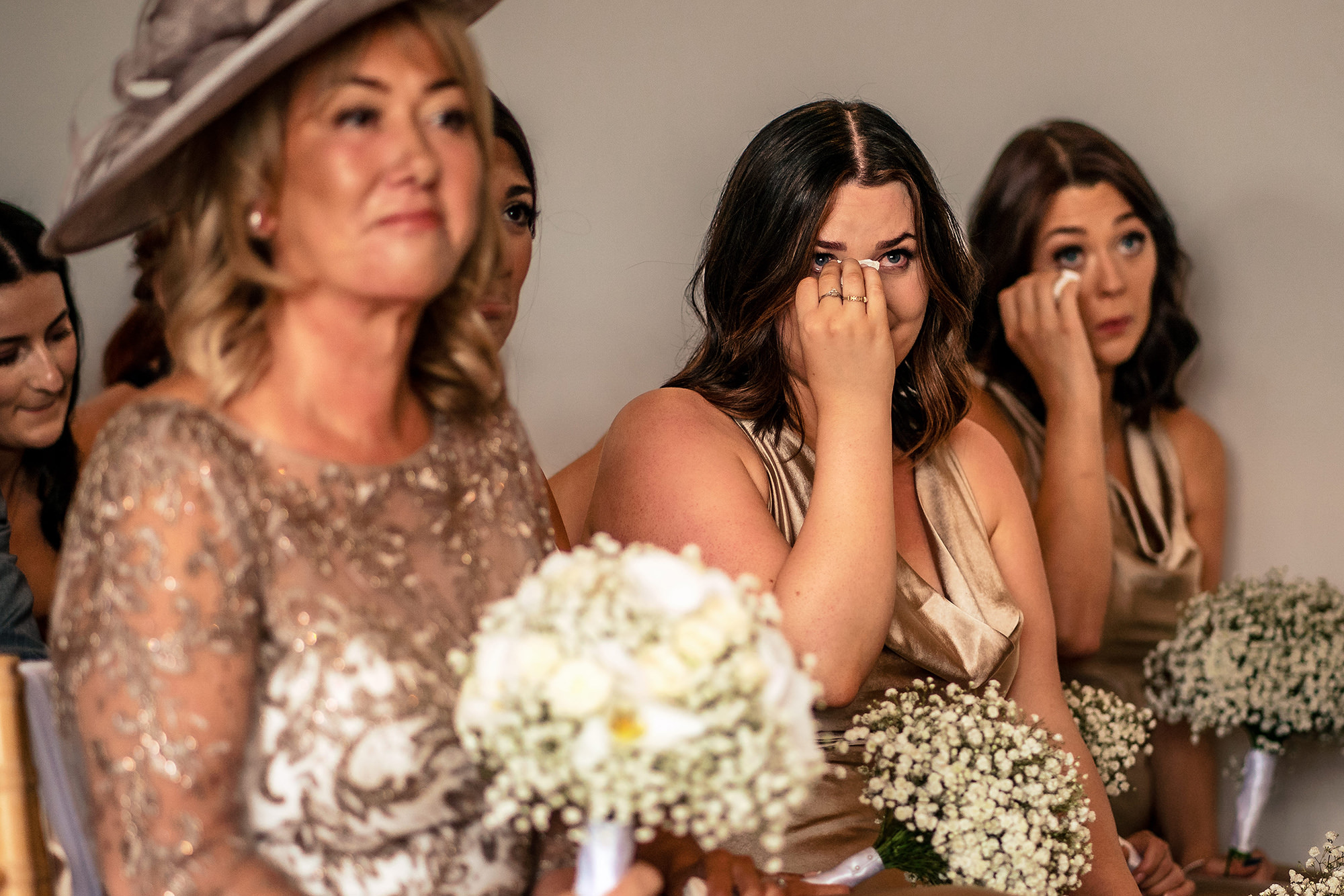 Bridesmaids and family wiping away tears during the ceremony at Salt House, a candid moment from a Staffordshire wedding