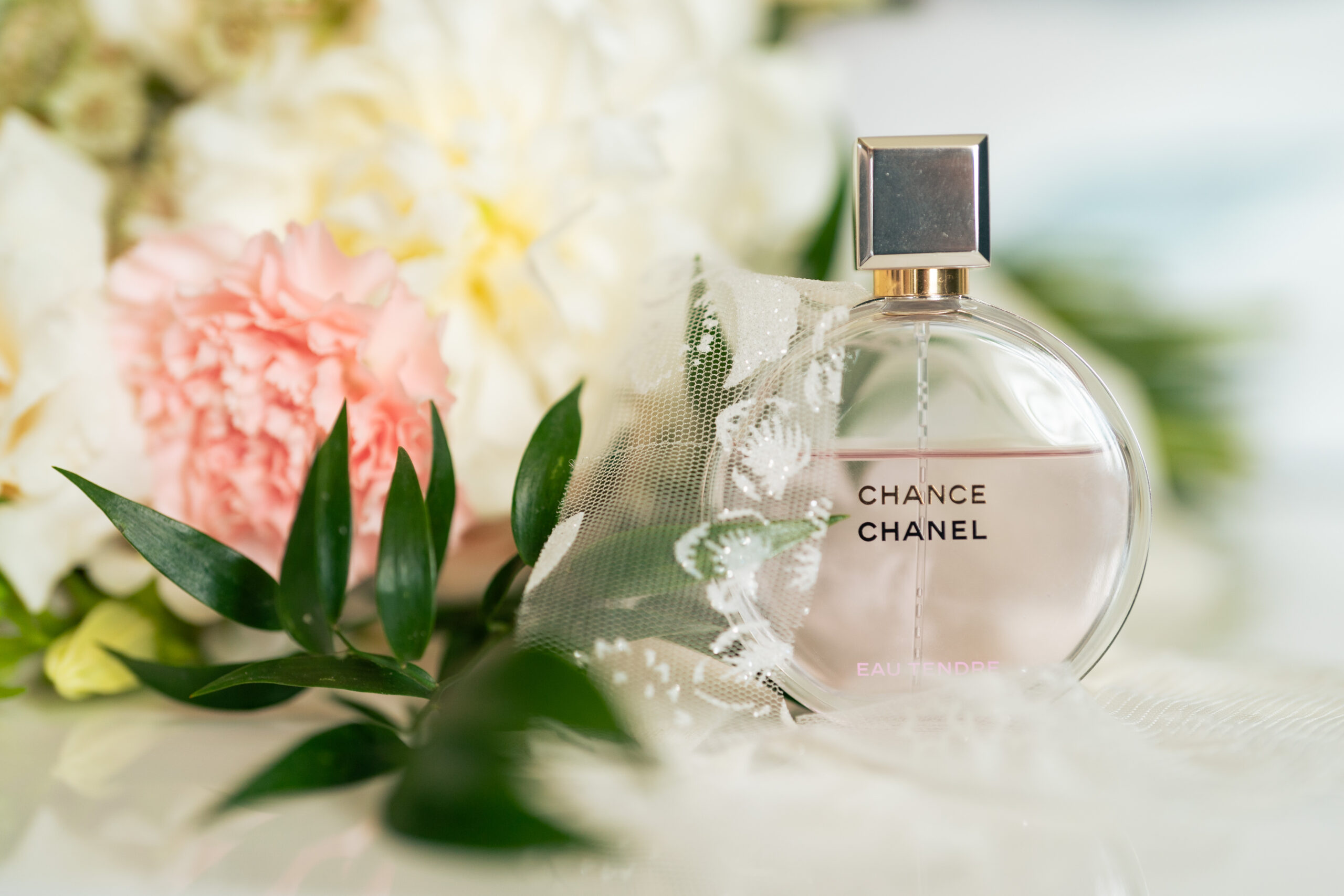 Bride’s perfume bottle next to peonies and roses, a detail shot from wedding morning prep at Salt House