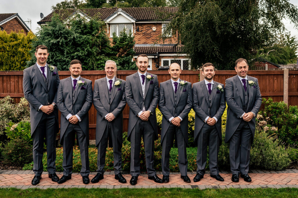 Groom and his groomsmen lined up in matching grey morning suits and purple ties, Cheshire wedding photographer