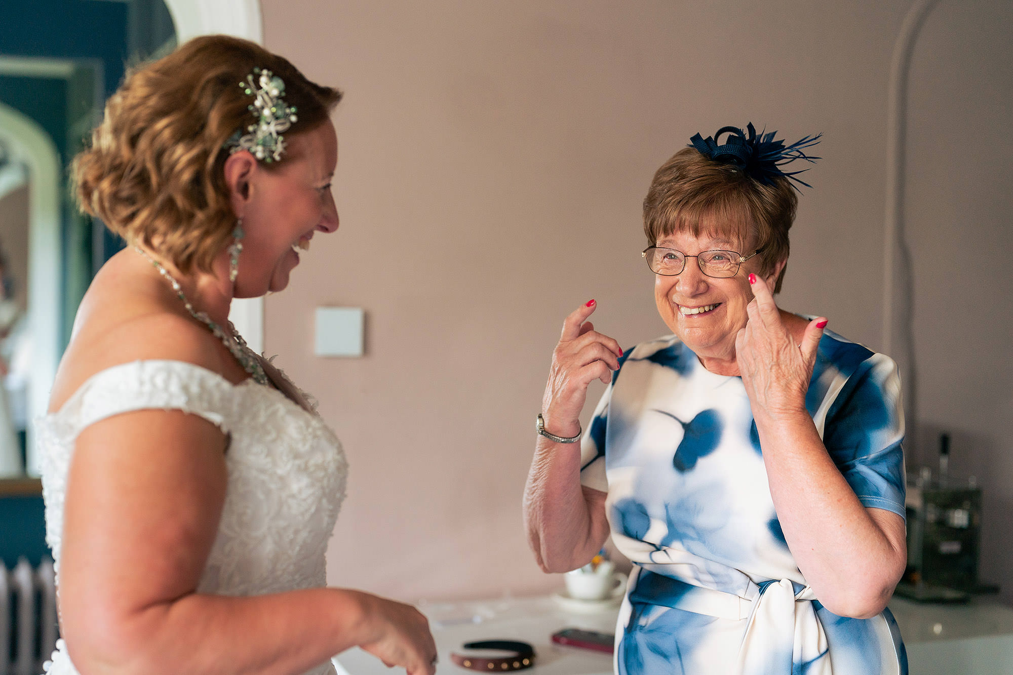 Bride laughing as a family member fixes her earring shortly before her Salt House wedding ceremony