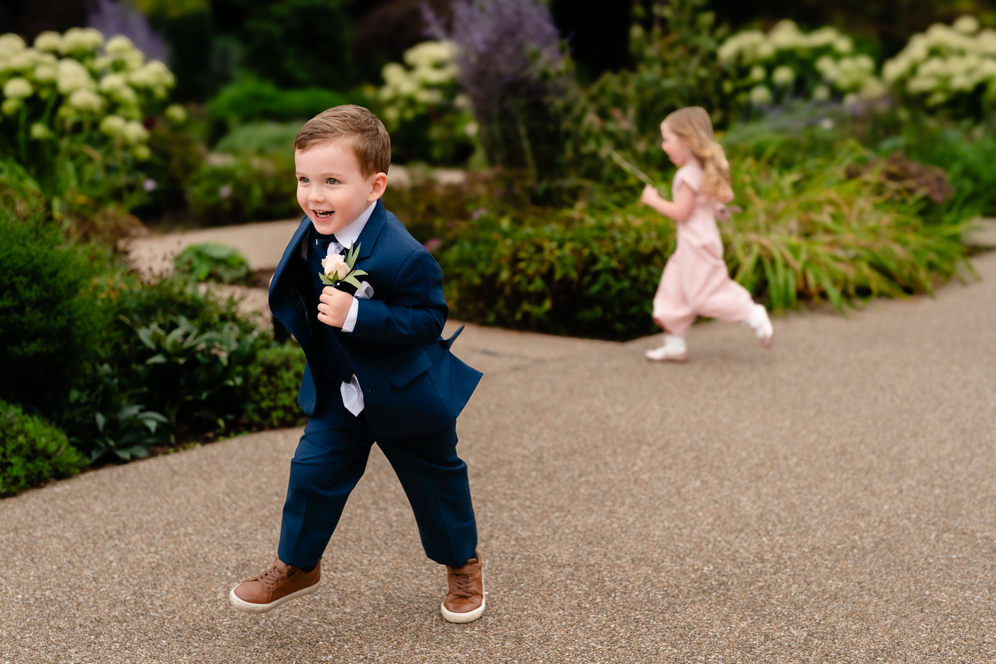 Pageboy and flower girl running and laughing through the gardens at Salt House, Staffordshire wedding photographer