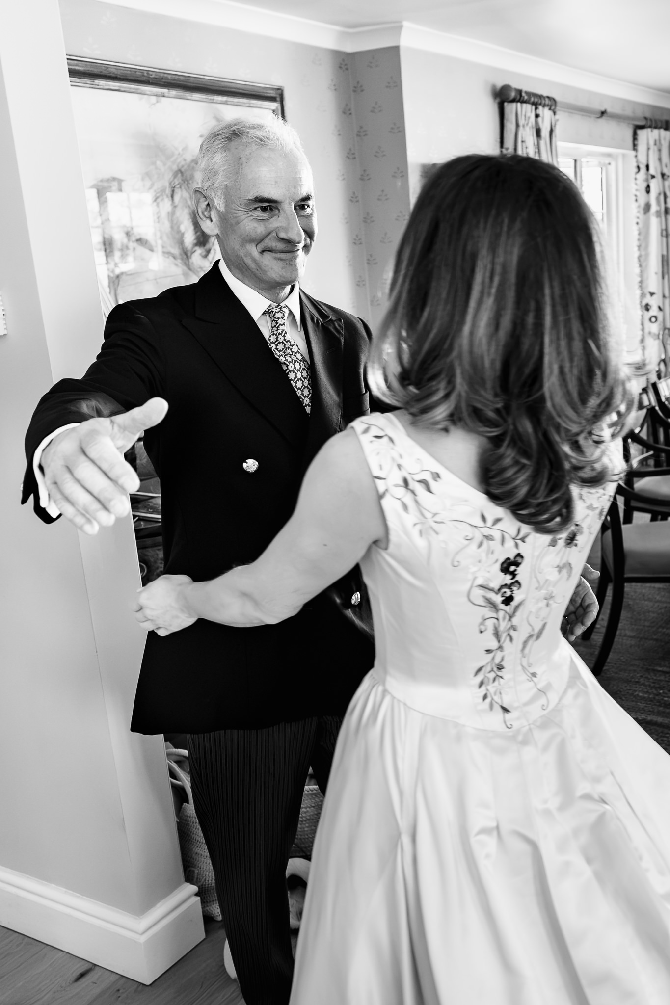 Father of the bride reaching out to his daughter as he sees her in her dress for the first time