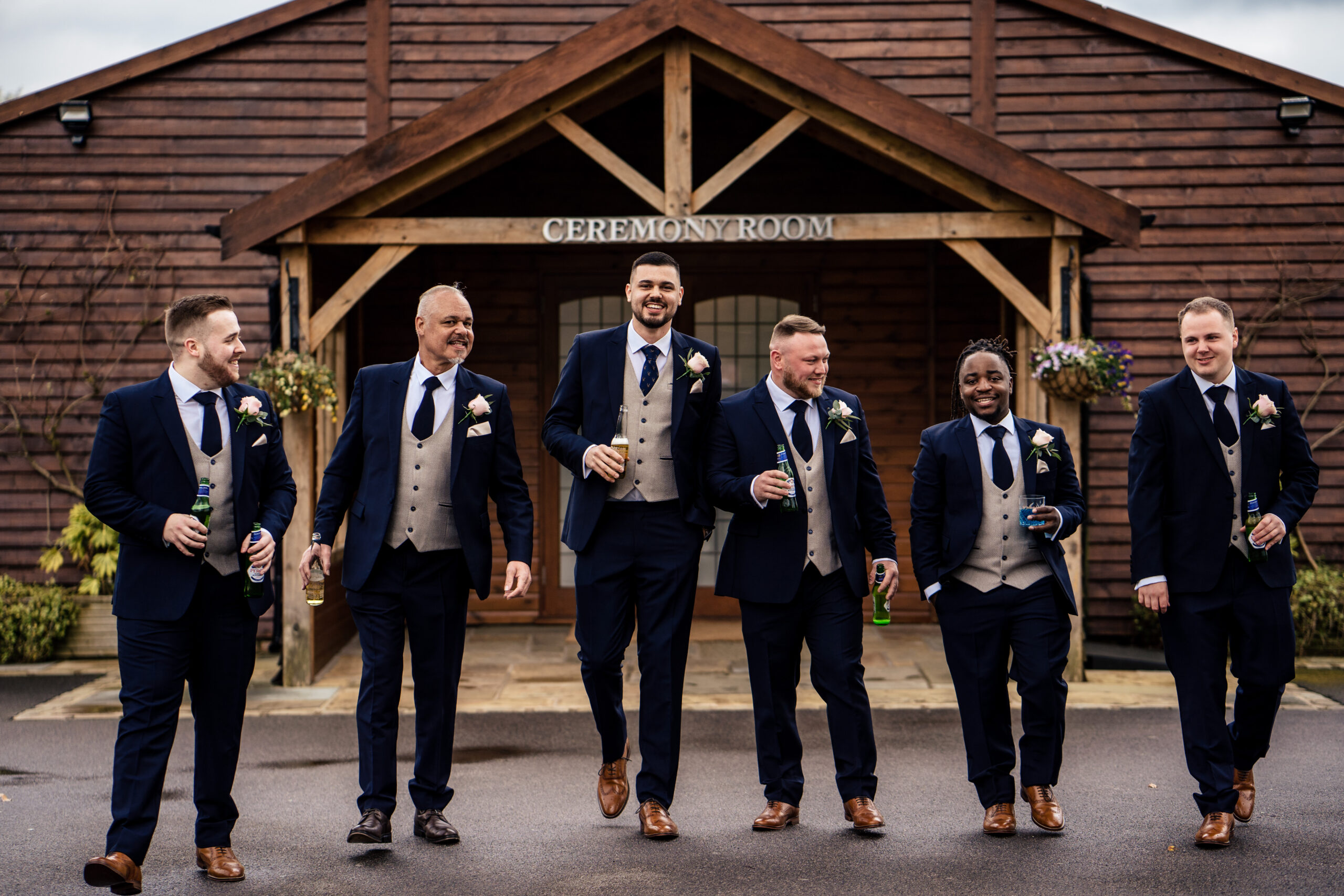 Dean and the men of the wedding party walking in navy suits outside the Ceremony Room at Merrydale Manor