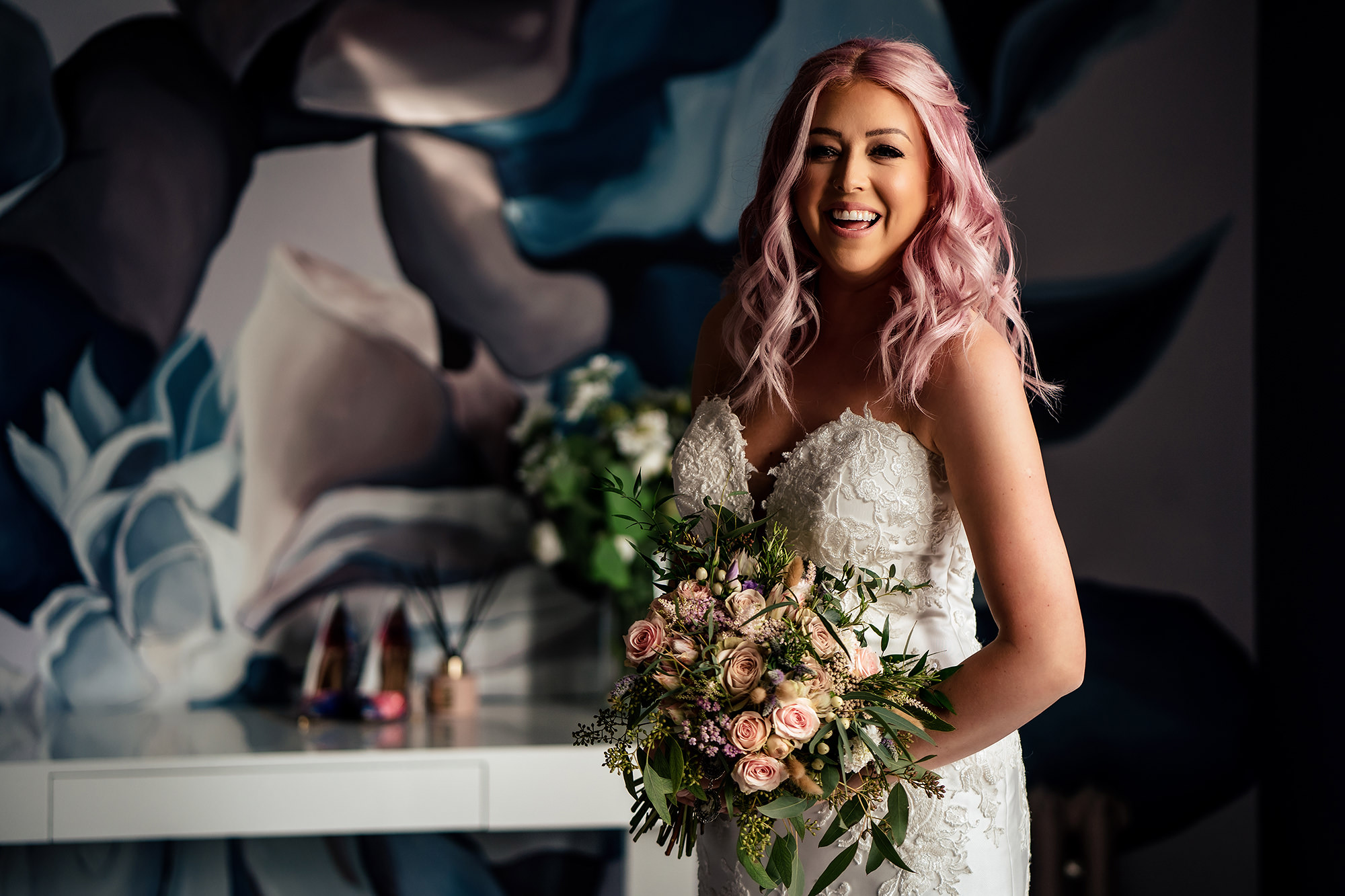Bride with pink hair laughing while holding her bouquet before her Standon Hall wedding