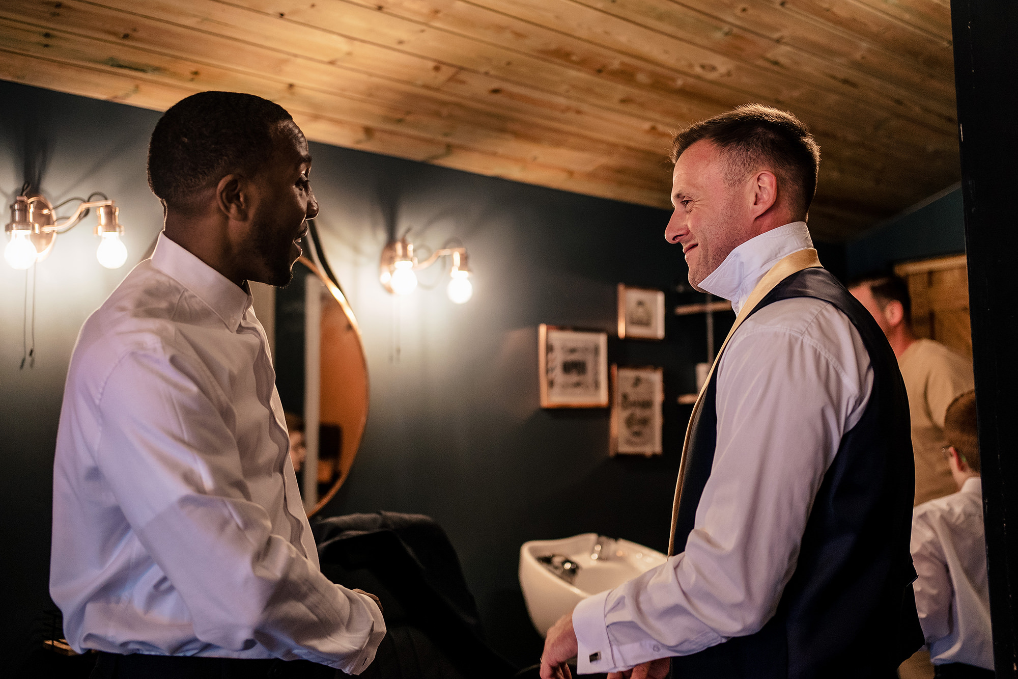 A quiet word between two groomsmen by the mirror, Merrydale Manor wedding photographer