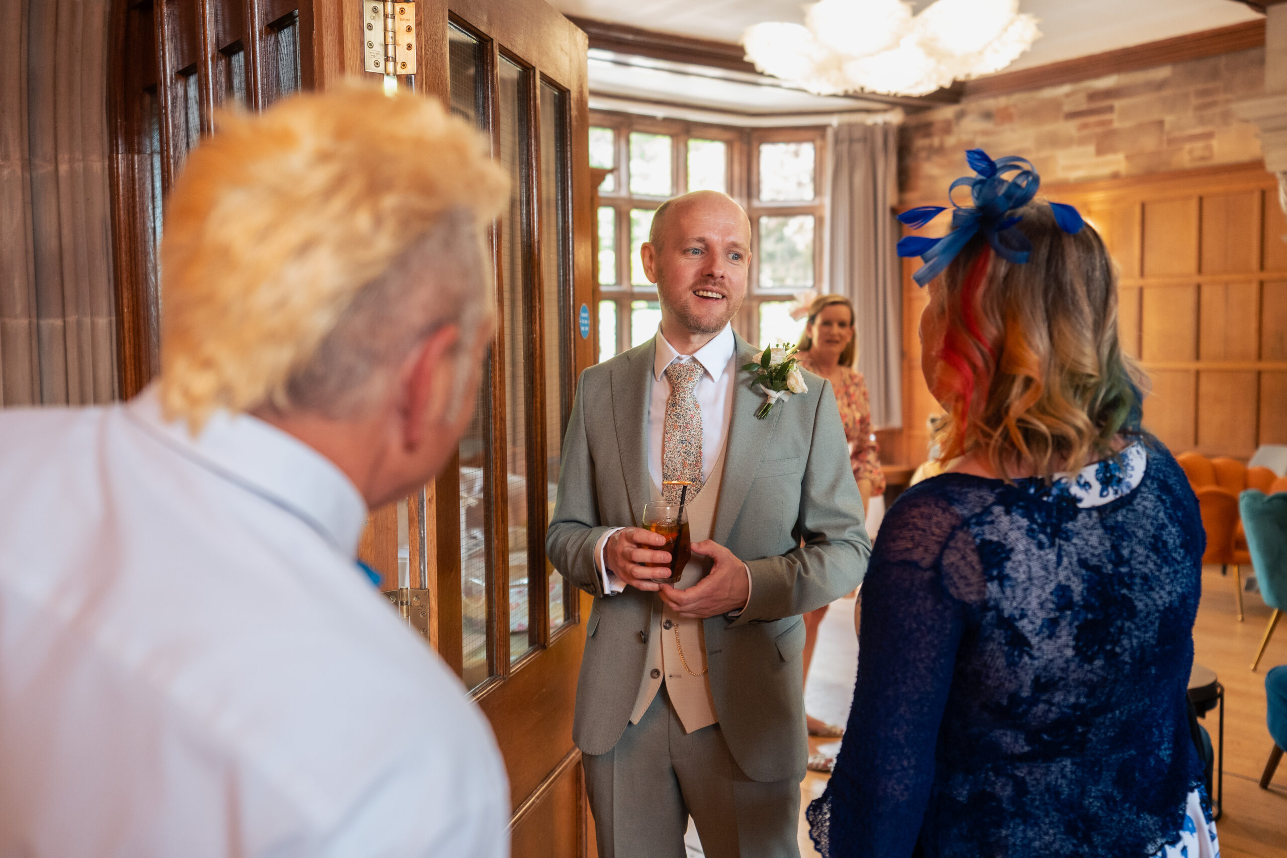 Groom chatting with an early arriving guest inside Salt House before his wedding ceremony