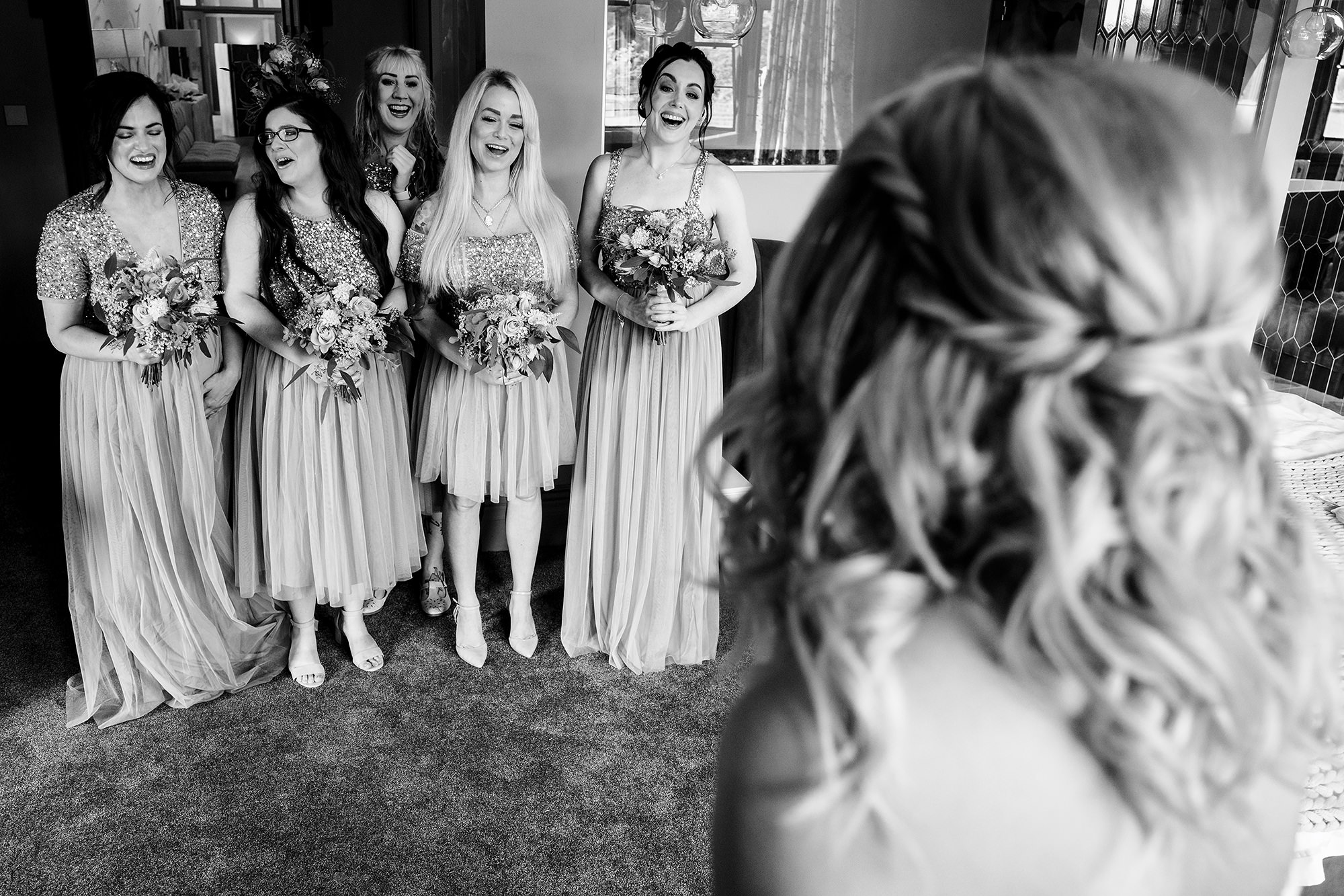 Bridesmaids reacting with delight as they see the bride ready for her Standon Hall wedding