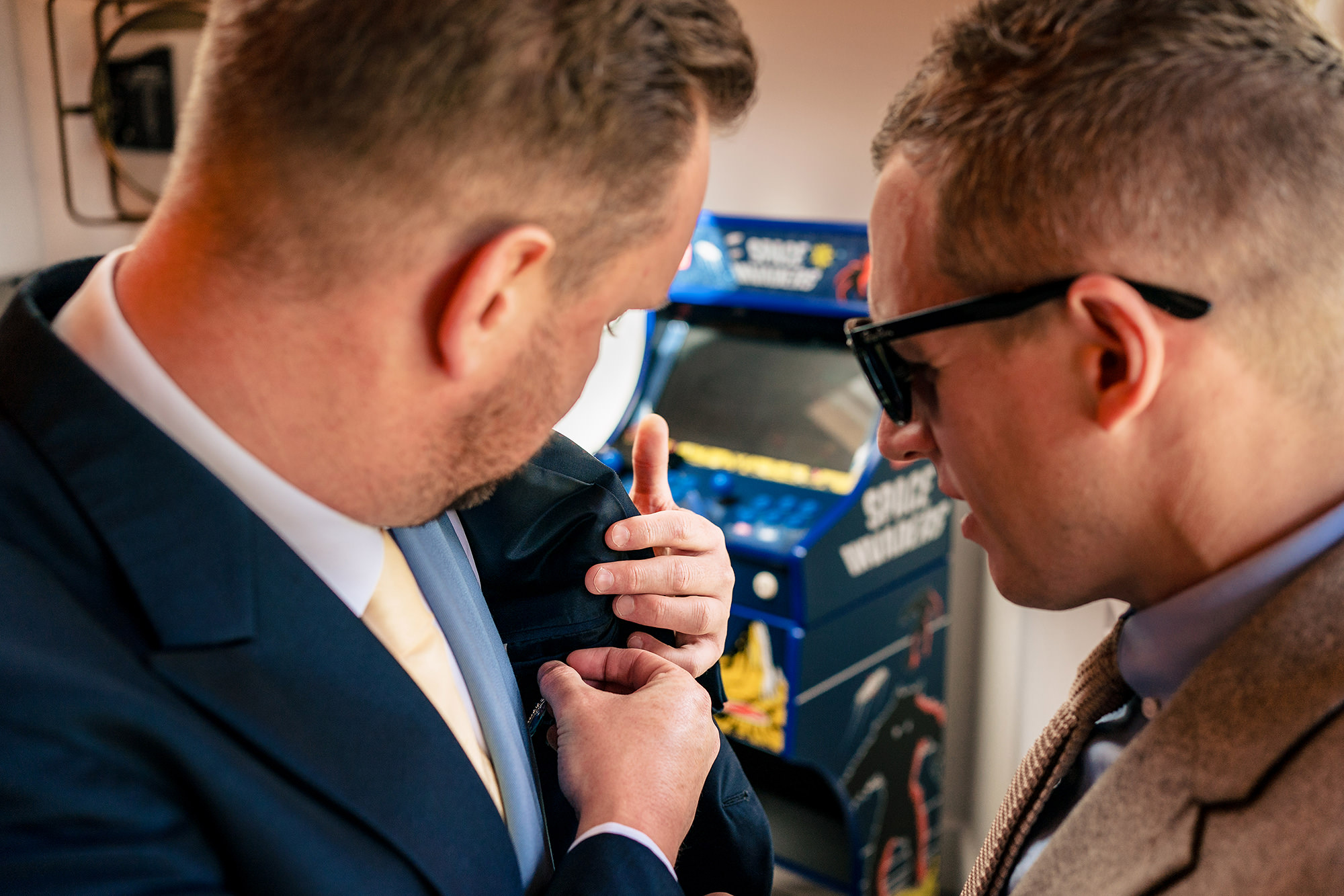 A last minute suit jacket adjustment next to the arcade machine, Merrydale Manor wedding photographer