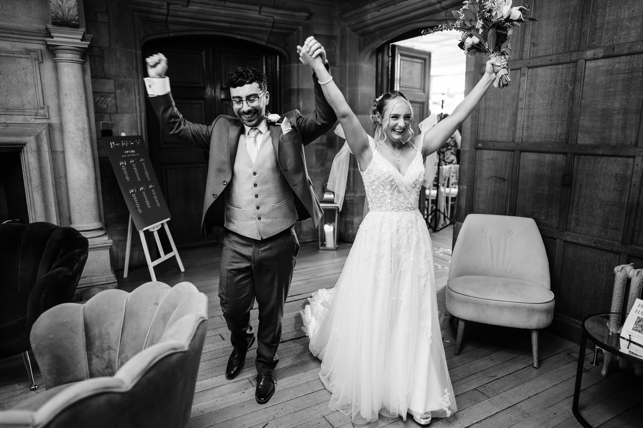 Black and white photo of the newly married couple celebrating with arms raised at Salt House