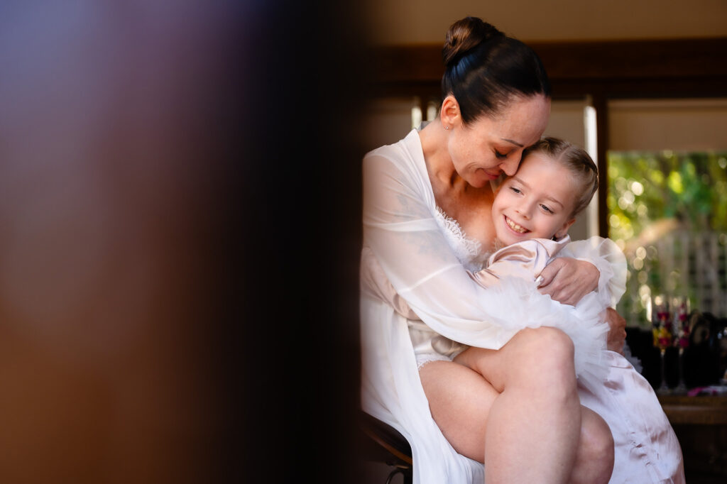 Kim hugging a smiling little girl in a white tulle dress on the wedding morning, Nottingham wedding photographer