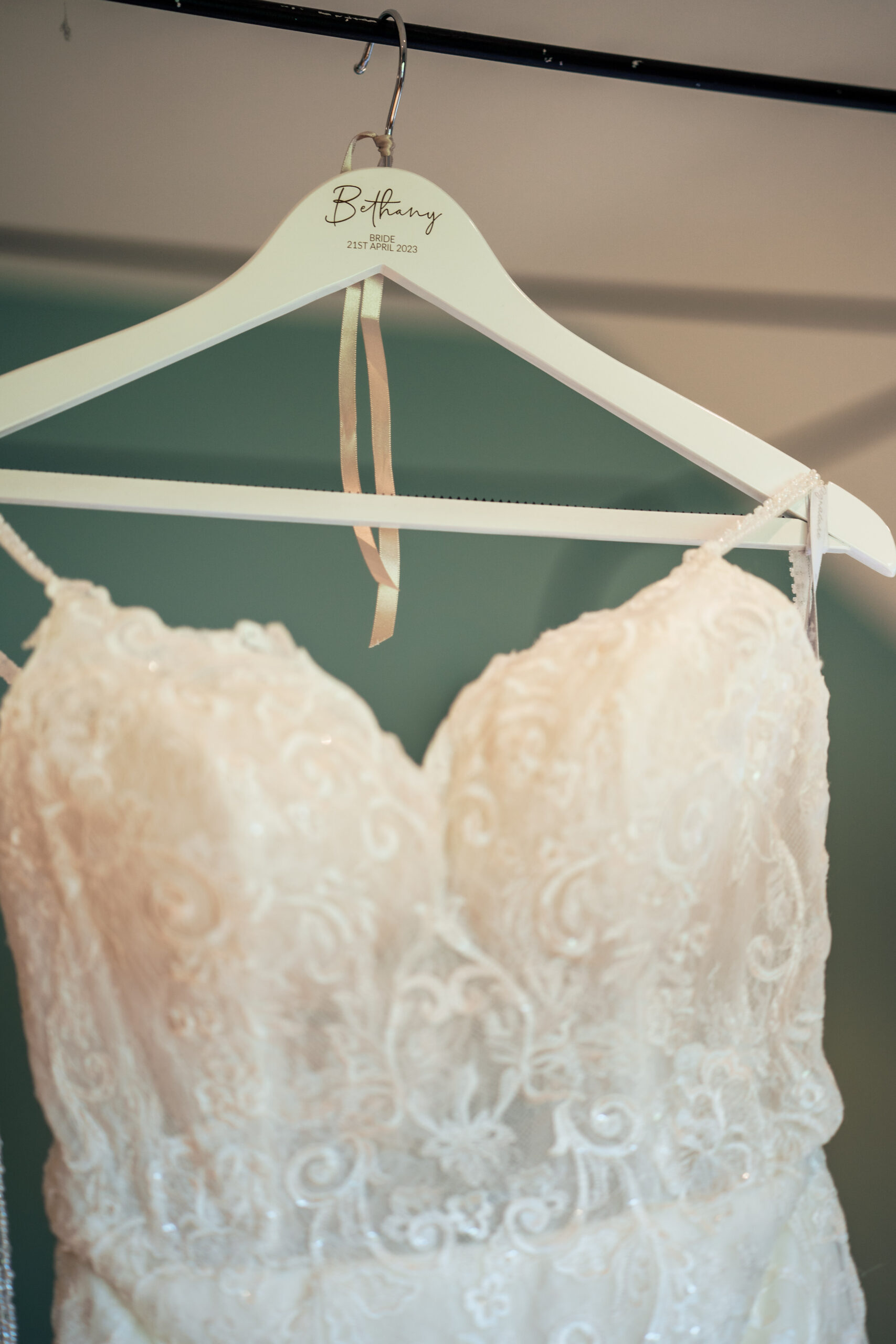 Lace wedding dress hanging on a personalised Bethany hanger in the bridal suite