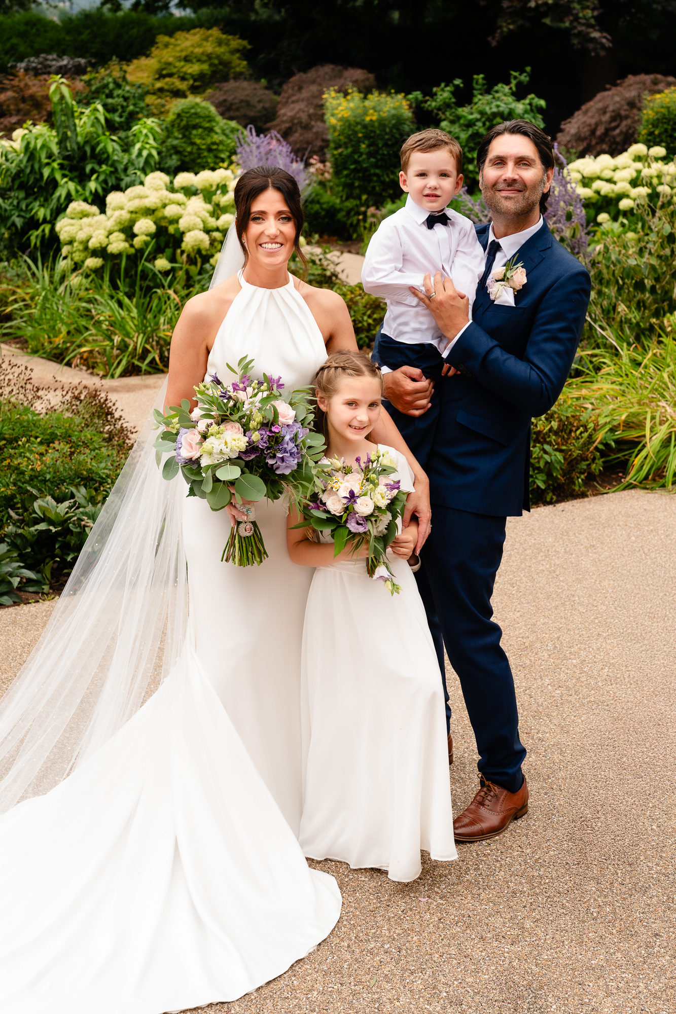 Bride and groom with their children smiling in the gardens at Salt House, Staffordshire wedding photographer