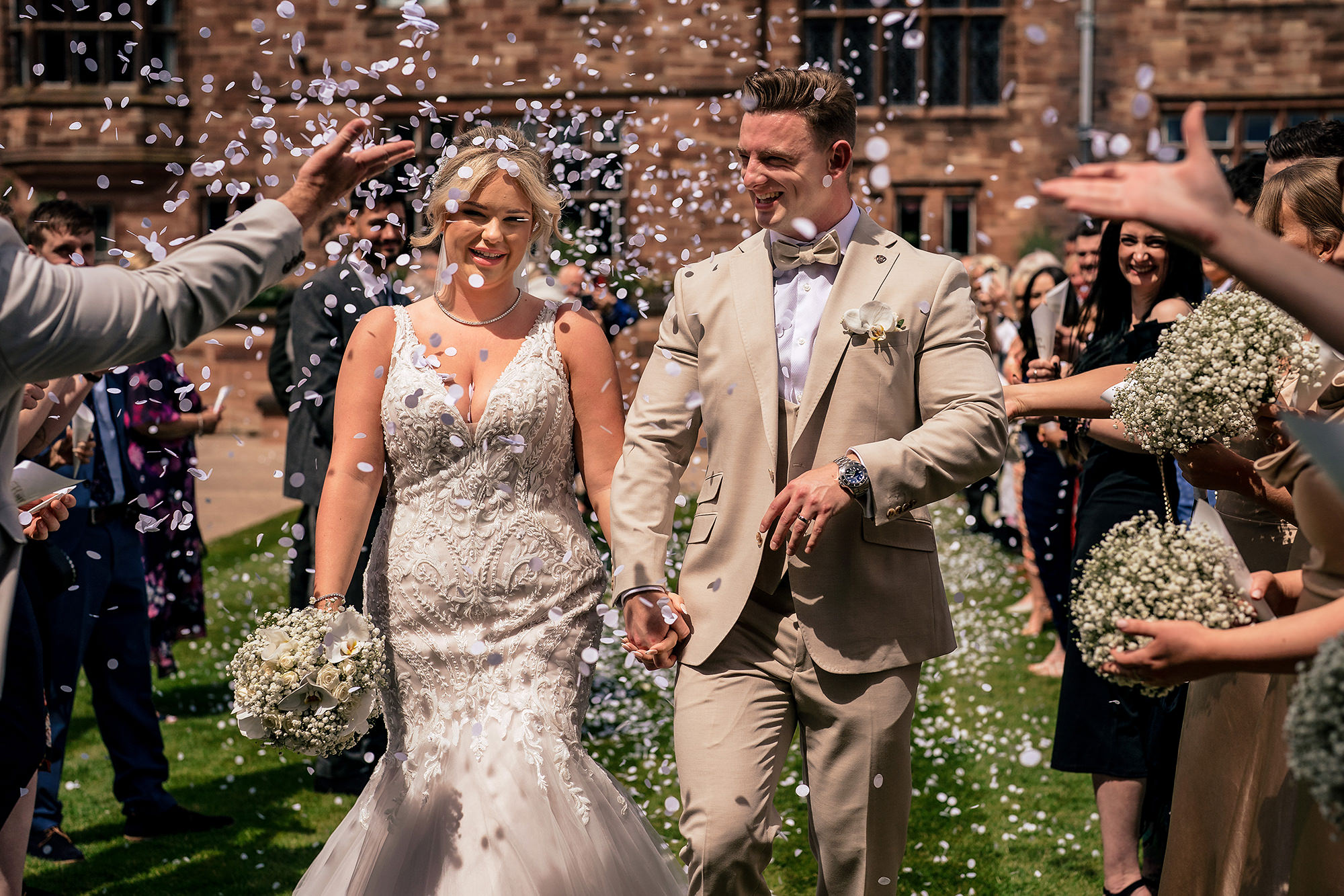 Jess and Cy walking hand in hand through confetti outside Salt House, Staffordshire
