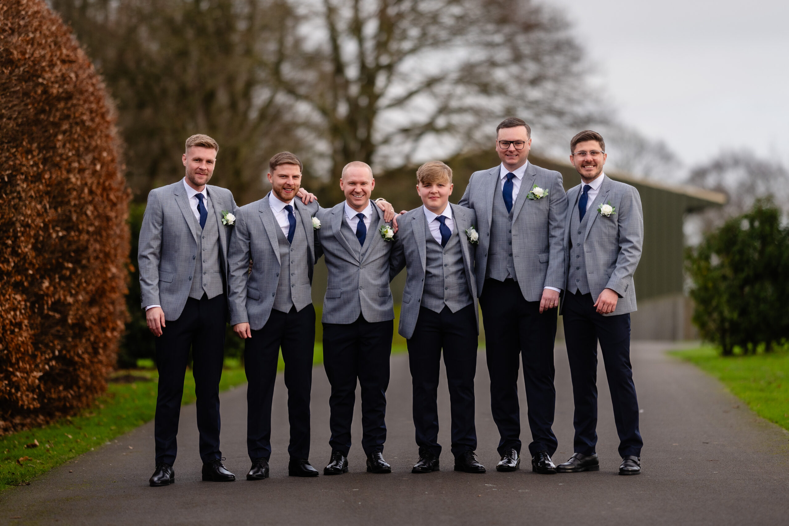 Groom and his groomsmen in grey suits and navy ties lined up on the drive at Colshaw Hall, Cheshire wedding photographer