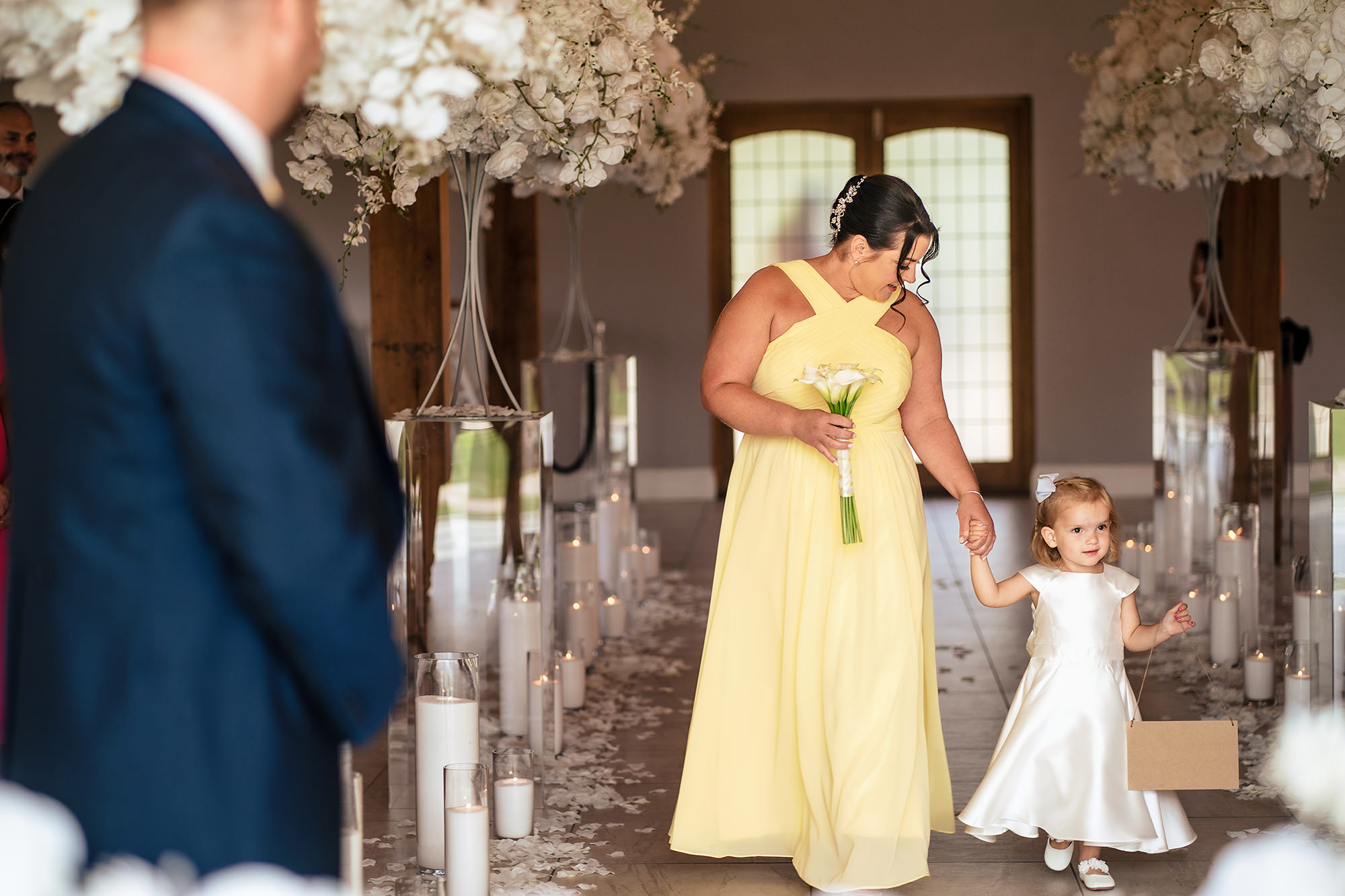 A bridesmaid in yellow leading a flower girl down the aisle, Merrydale Manor wedding photographer