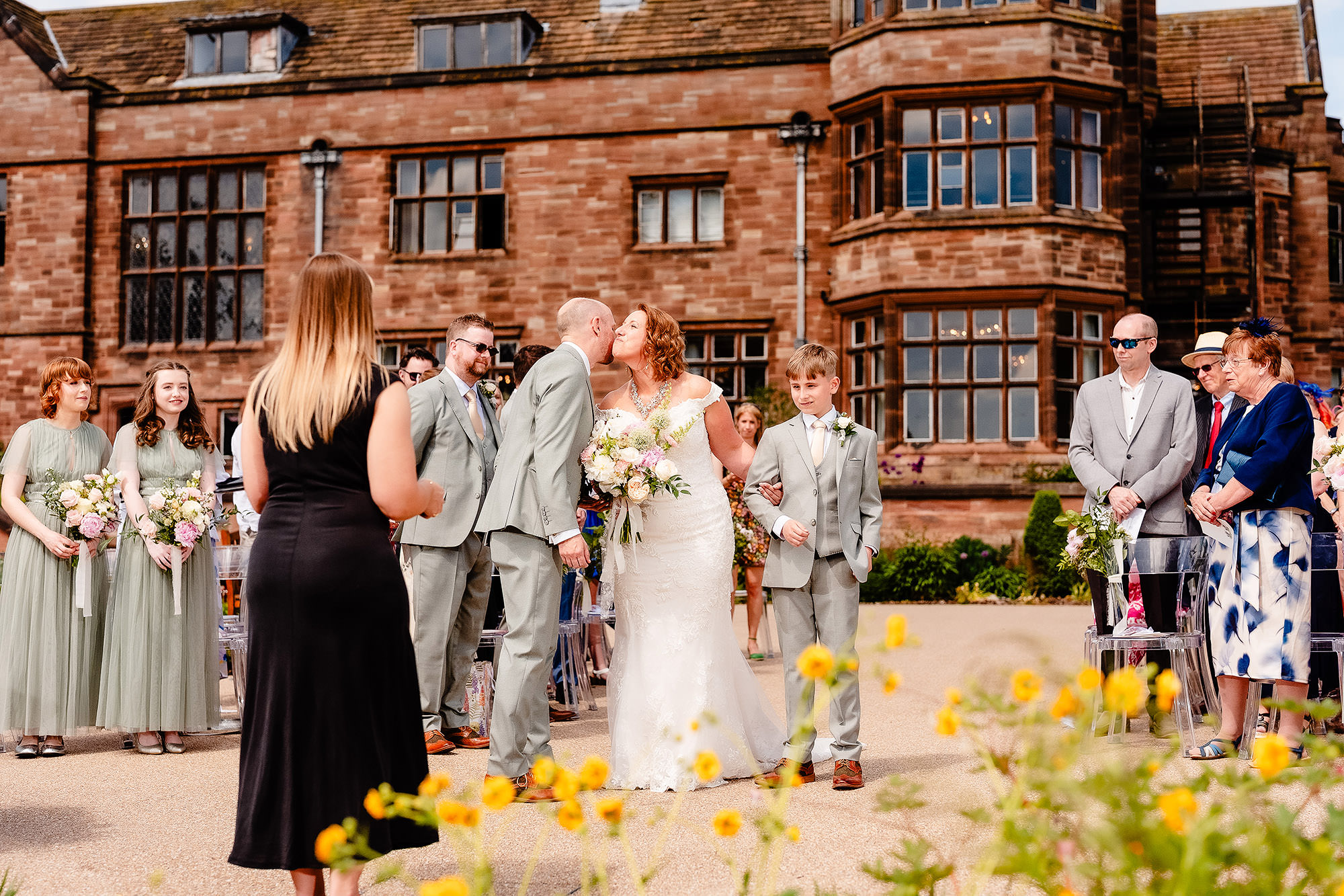 Bride being warmly greeted by a guest in the gardens at Salt House as the ceremony gets underway