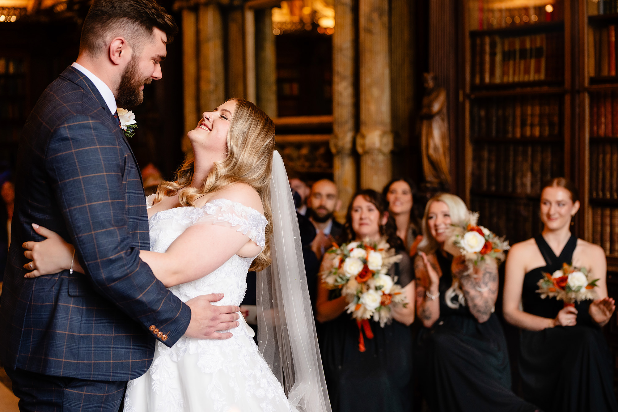 Annie and Tom embracing at the altar as guests look on, Crewe Hall wedding photographer
